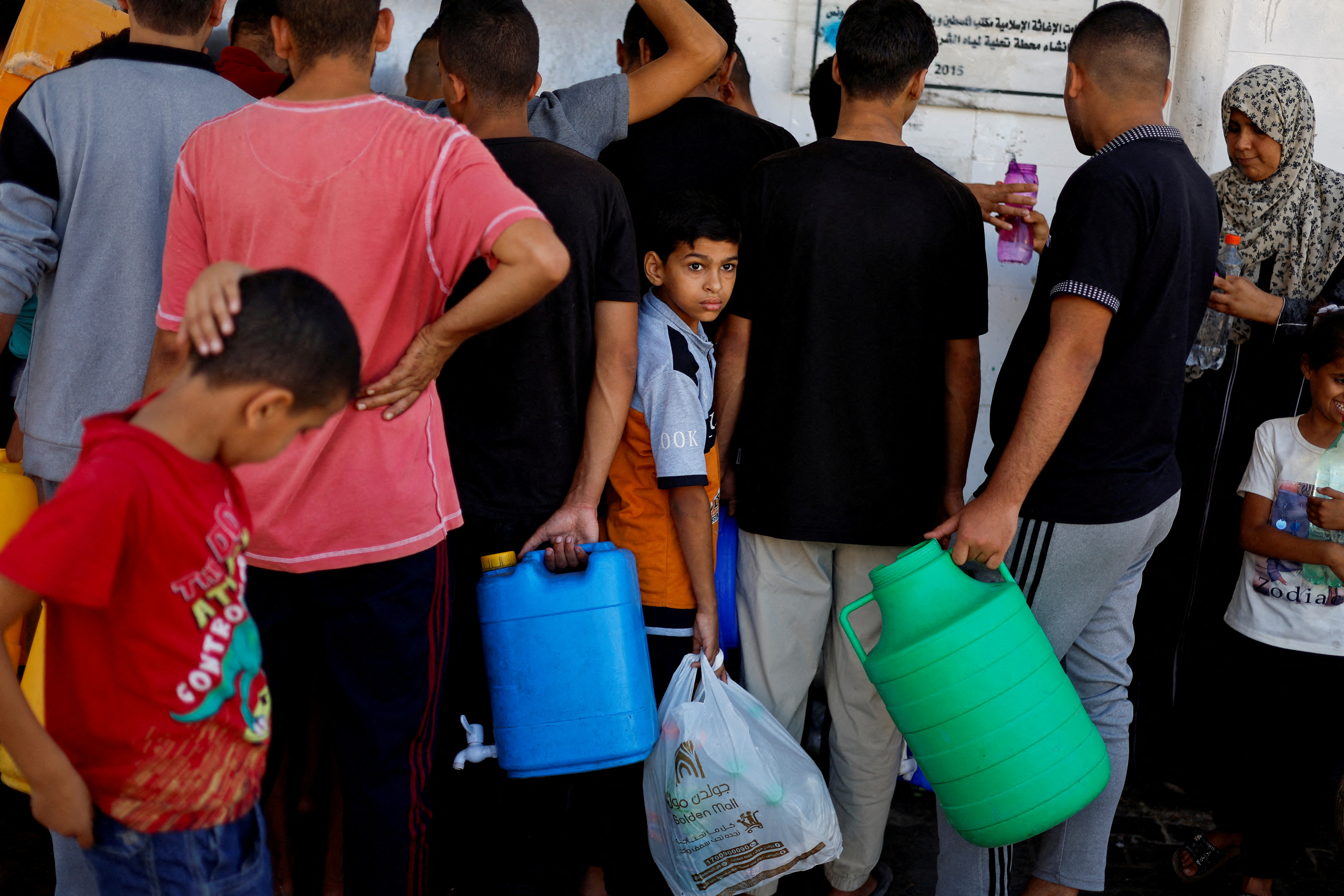 Palestinians gather to collect water, amid shortages of drinking water, as the Israeli-Palestinian conflict continues, in Khan Younis
