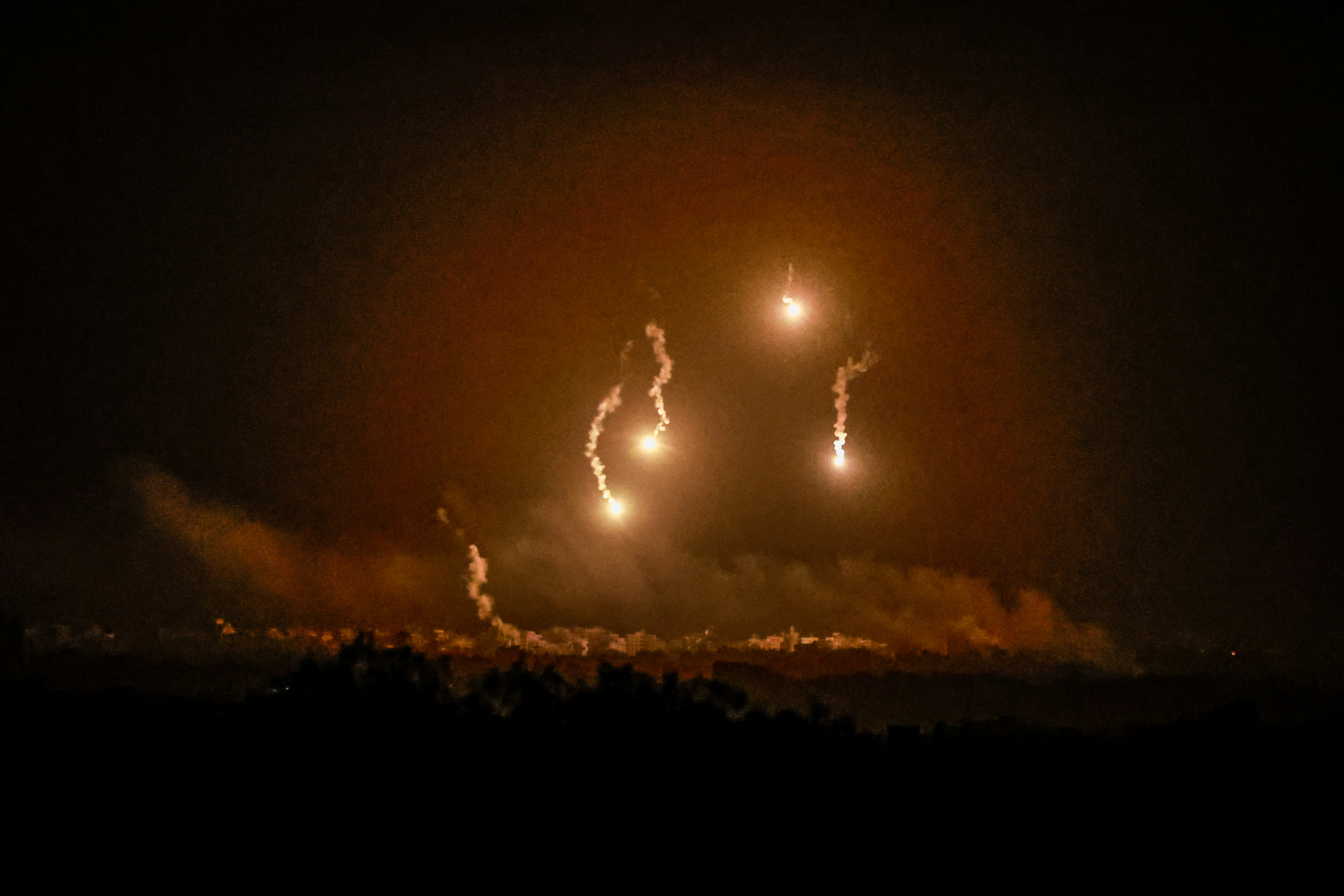 Flares burn in the sky as seen from the Israeli side of the border with Gaza