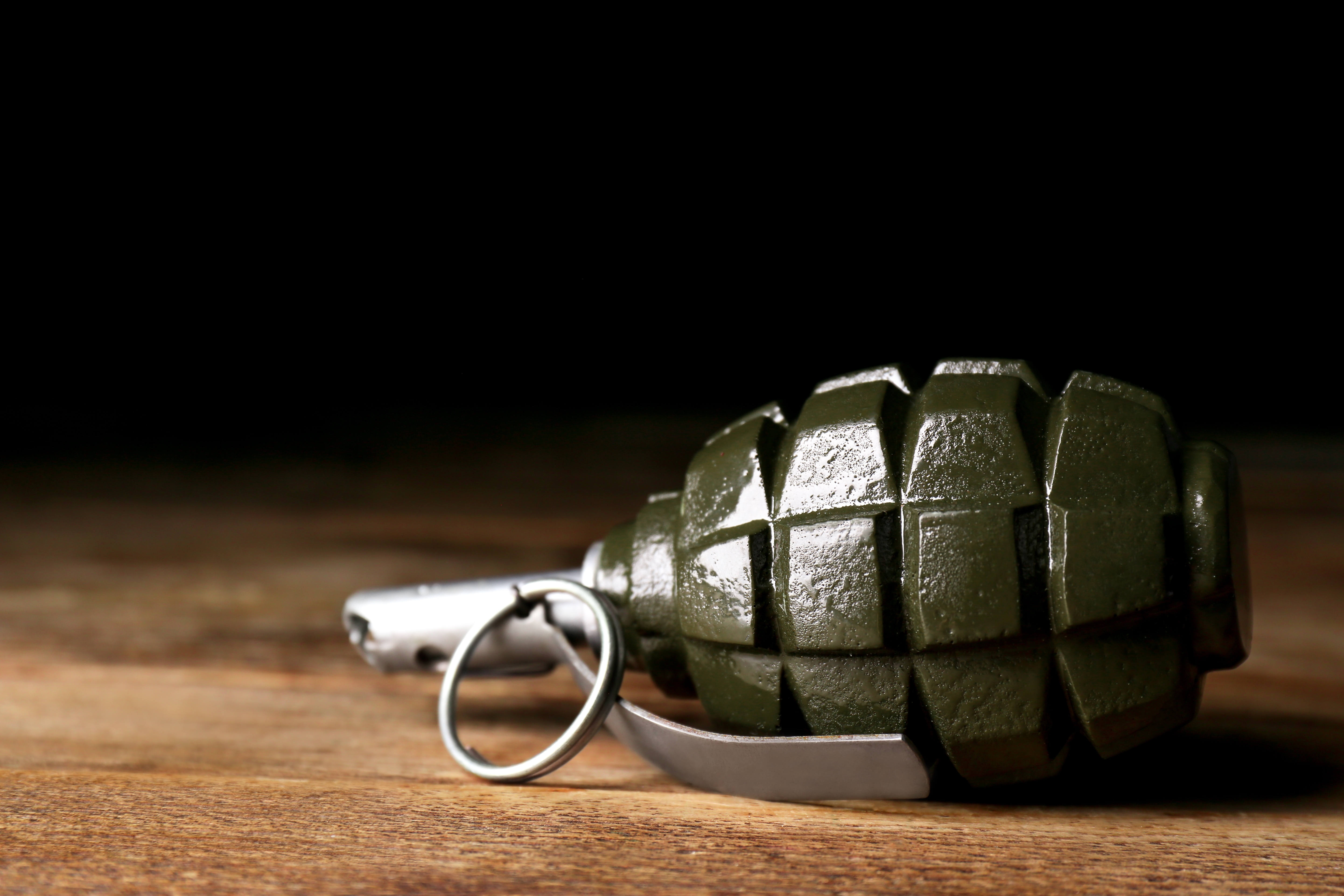 Hand,Grenade,On,Wooden,Table,Against,Black,Background,,Closeup.,Space
