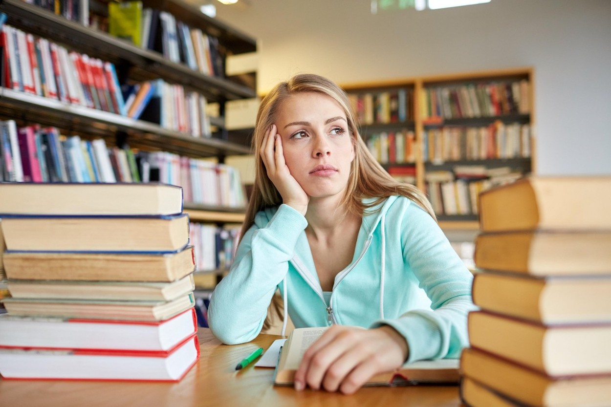 bored student or young woman with books in library