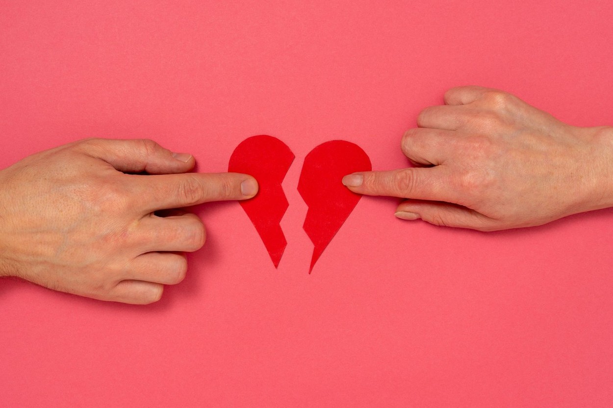 Love and relationship problems concept - male and female hands holding two parts of broken heart
