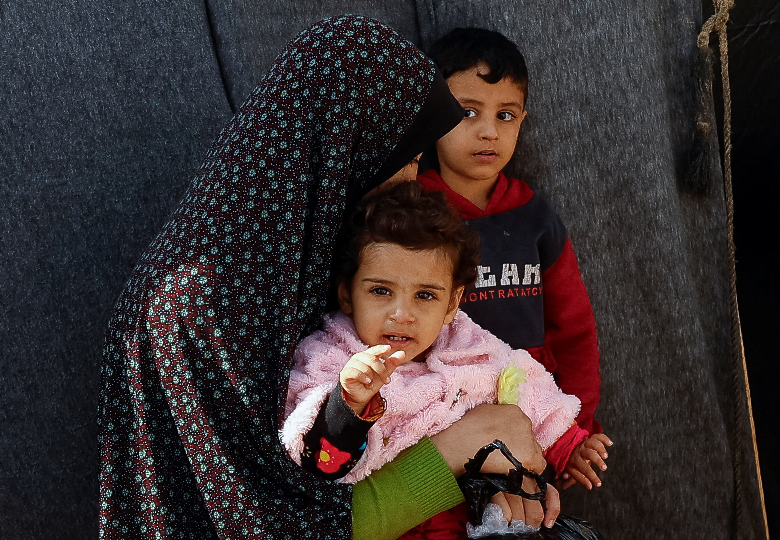 A displaced Palestinian woman sits with children, amid the ongoing conflict between Israel and Palestinian Islamist group Hamas, in a tent camp in Khan Younis in the southern Gaza Strip