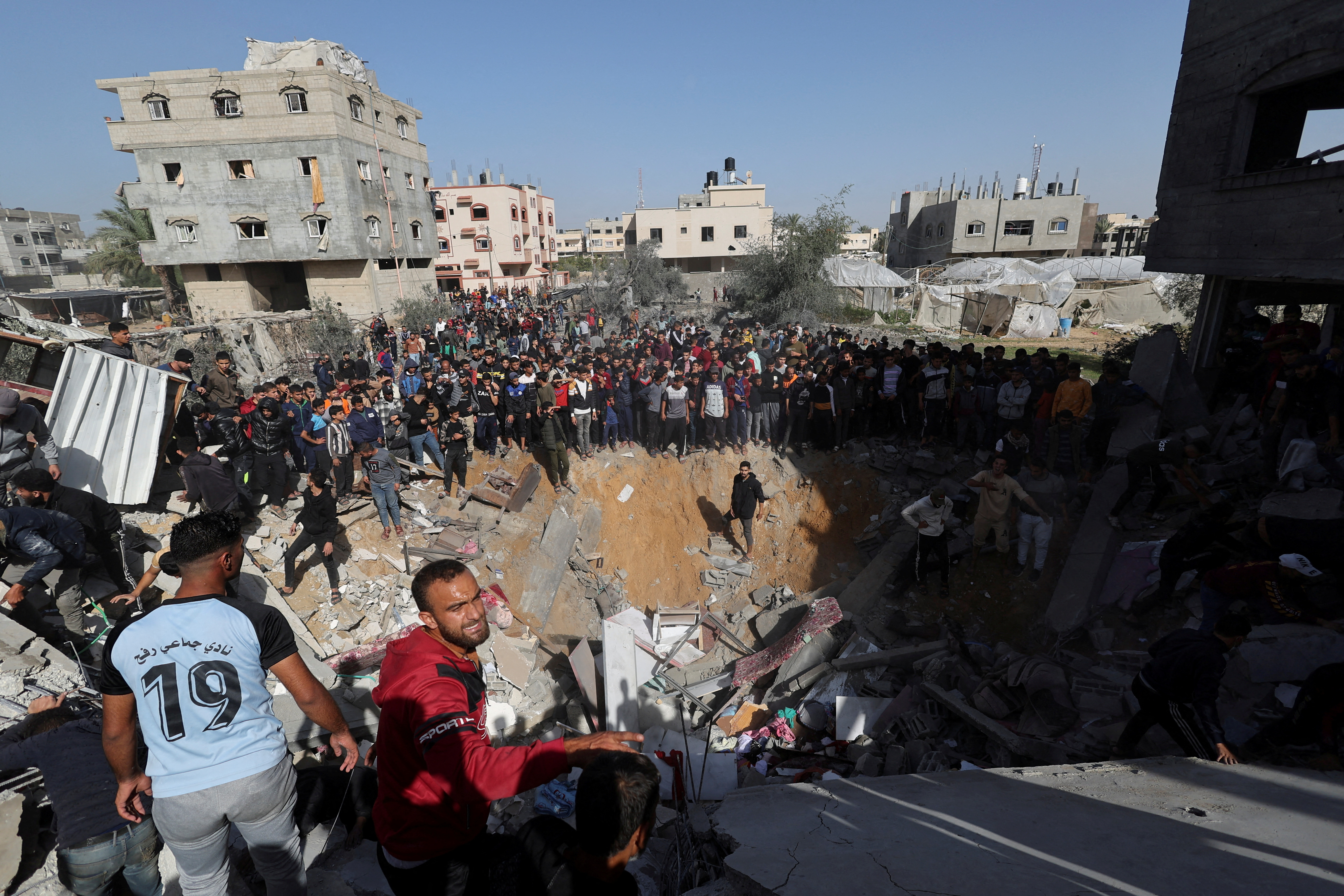 Palestinians gather as others search for casualties at the site of an Israeli strike on a house in Rafah, amid the ongoing conflict between Israel and the Palestinian Islamist group Hamas, in the southern Gaza Strip