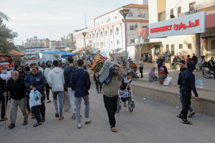 A displaced Palestinian man, who fled his house due to Israeli strikes, carries his belongings as he makes his way back to his home, in Khan Younis