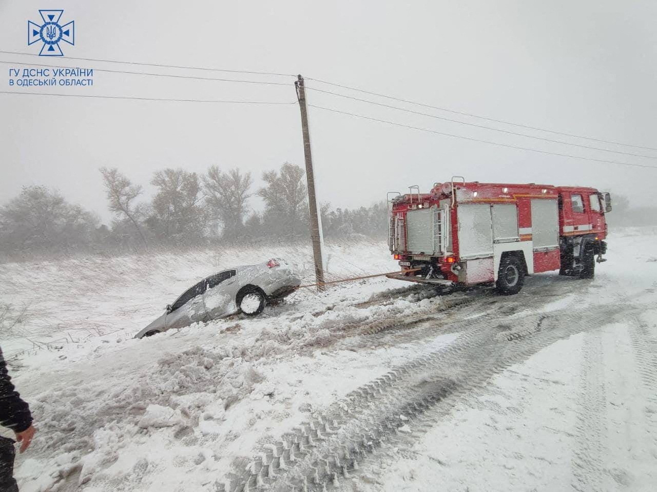 Emergency workers release a car which is stuck in snow during a heavy snow storm in Odesa region