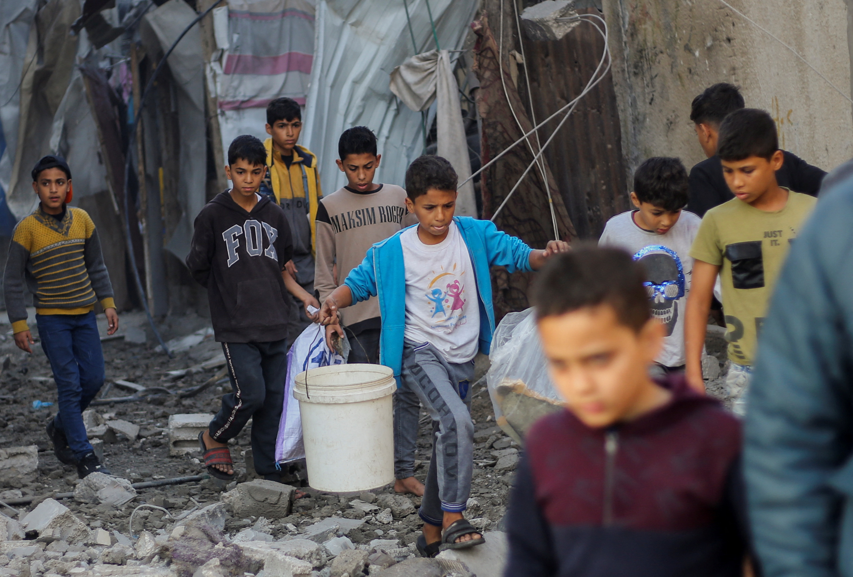 Palestinian children carry items as they walk at the site of Israeli strikes in Khan Younis