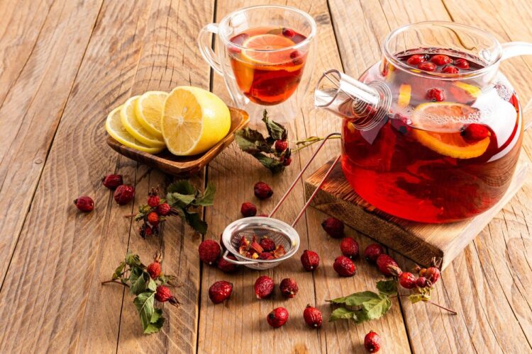 hot vitamin tea with rose hips stands on a wooden podium and a table with a cup of tea and lemon slices. phytotherapy. anti-cold drinks