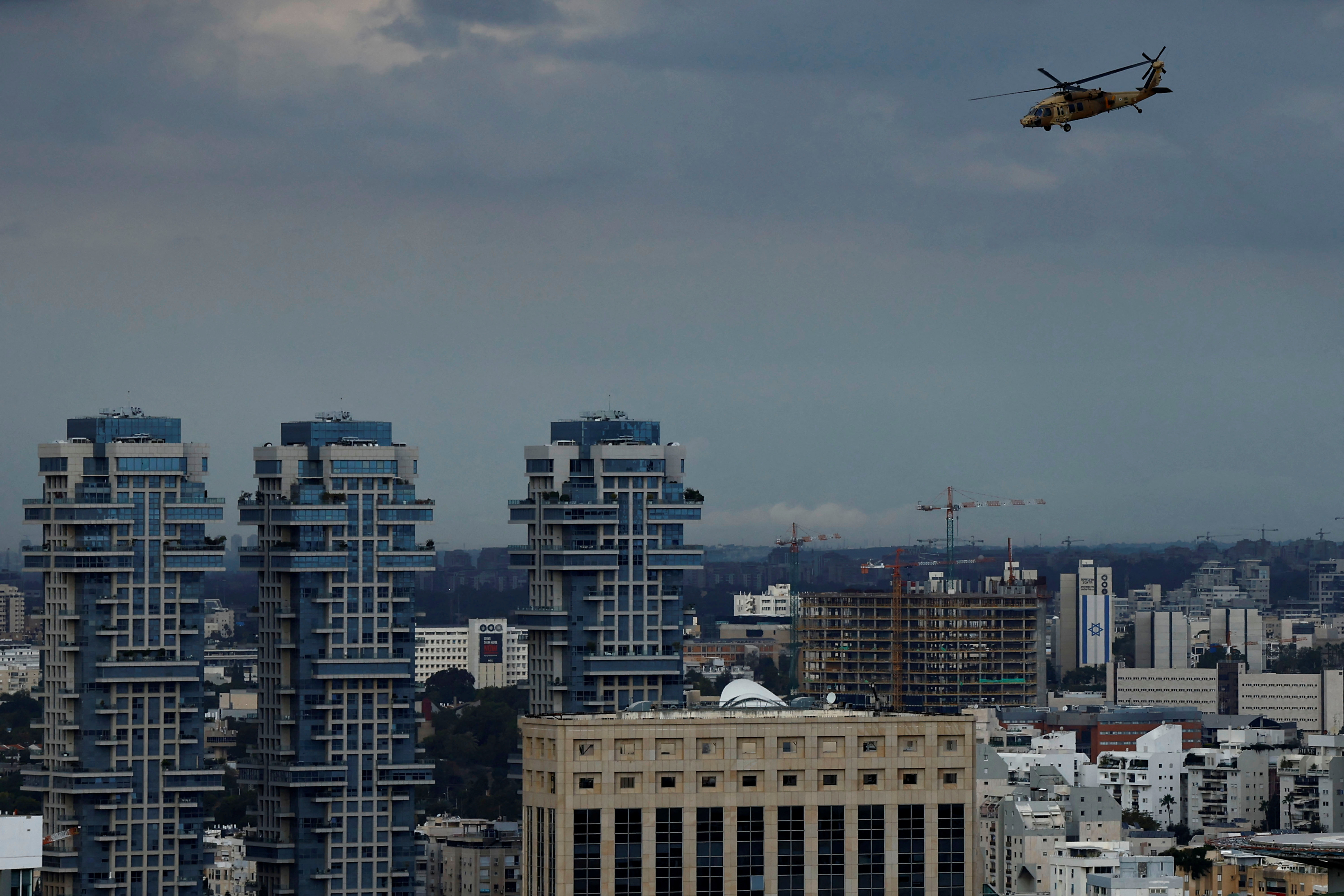 Israeli military helicopter flies near a high-rise building in Tel Aviv
