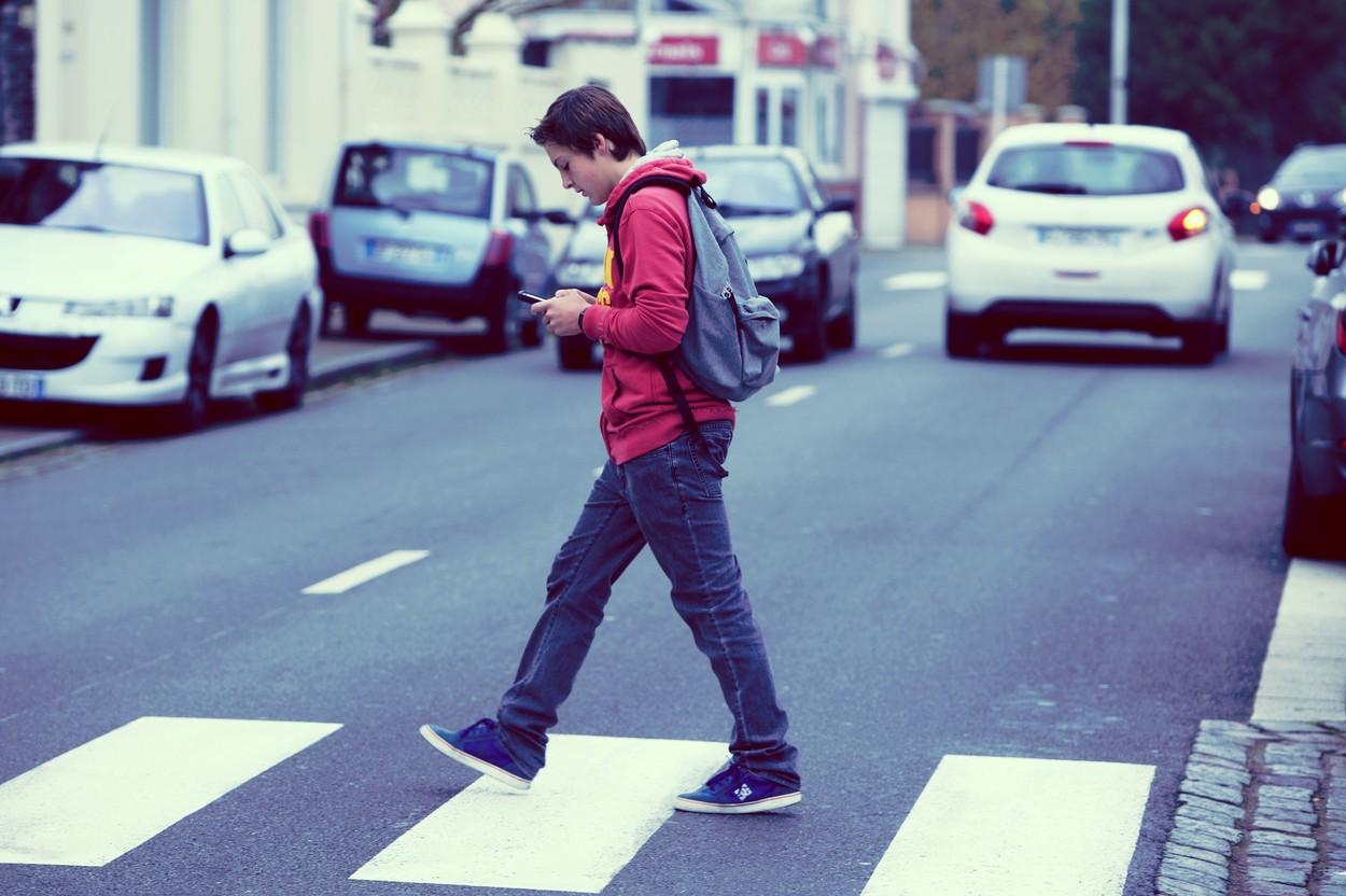 France, teenager walking while using his smartphone