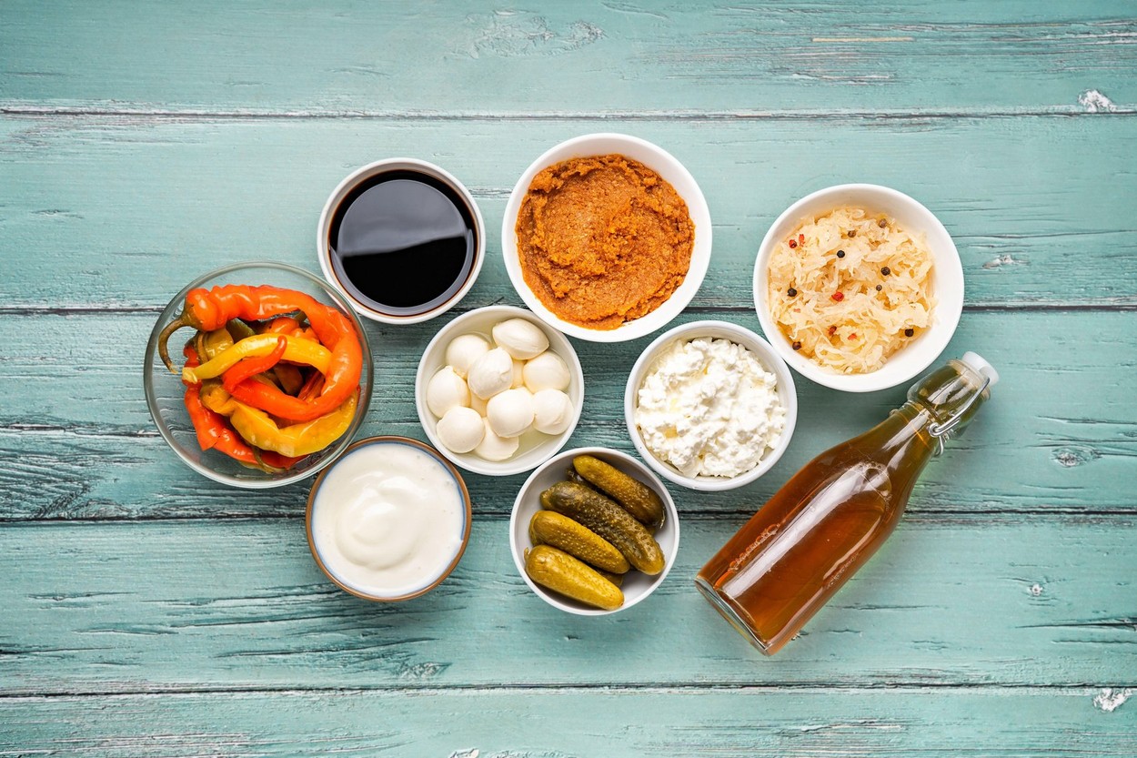 Variety of fermented foods uncluding pickles, sauerkraut, soy sauce, miso, diary and apple vinegar on light turquoise background. Healthy food concept