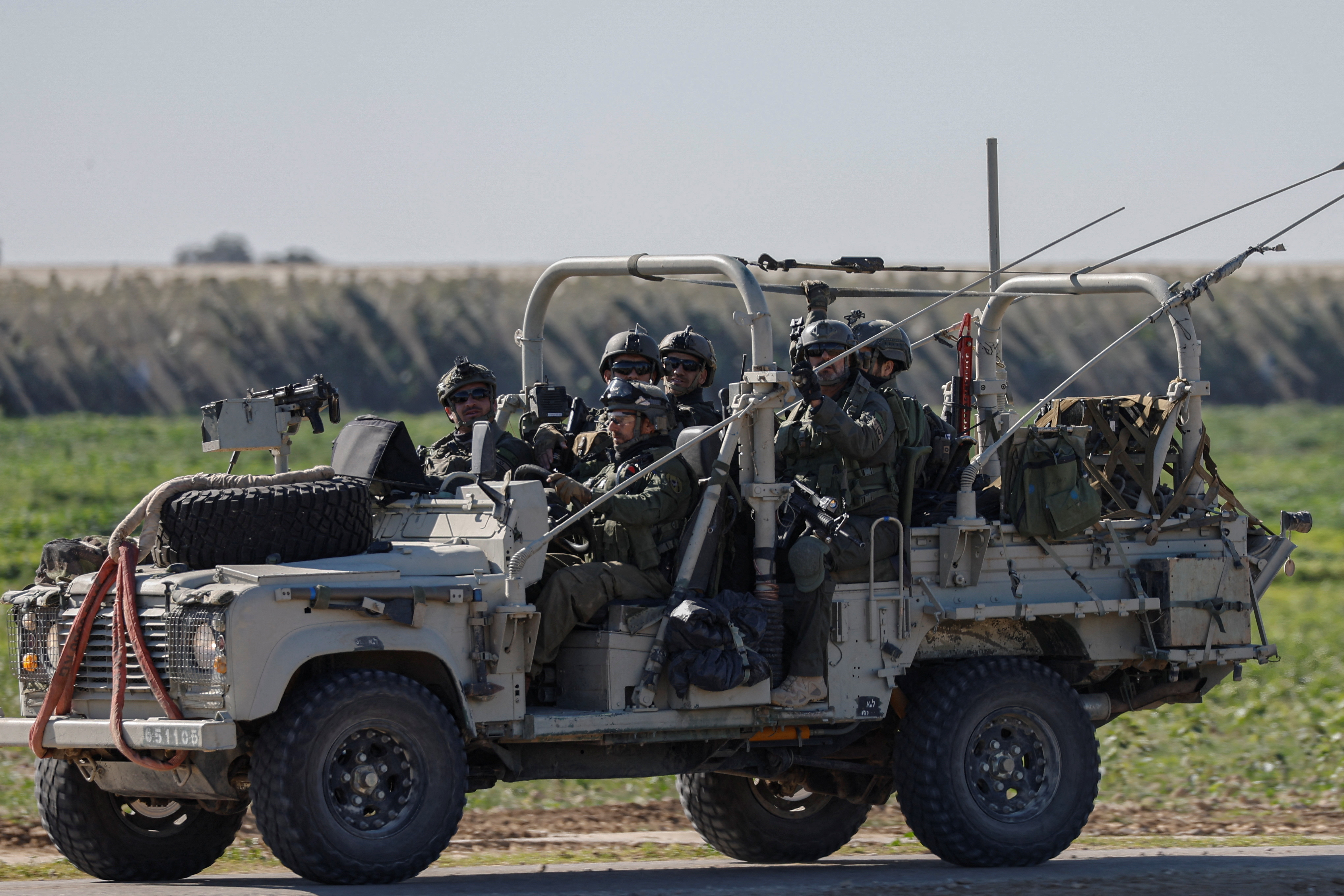 Israeli soldiers ride a military vehicle as they leave Gaza, near the Israel-Gaza border