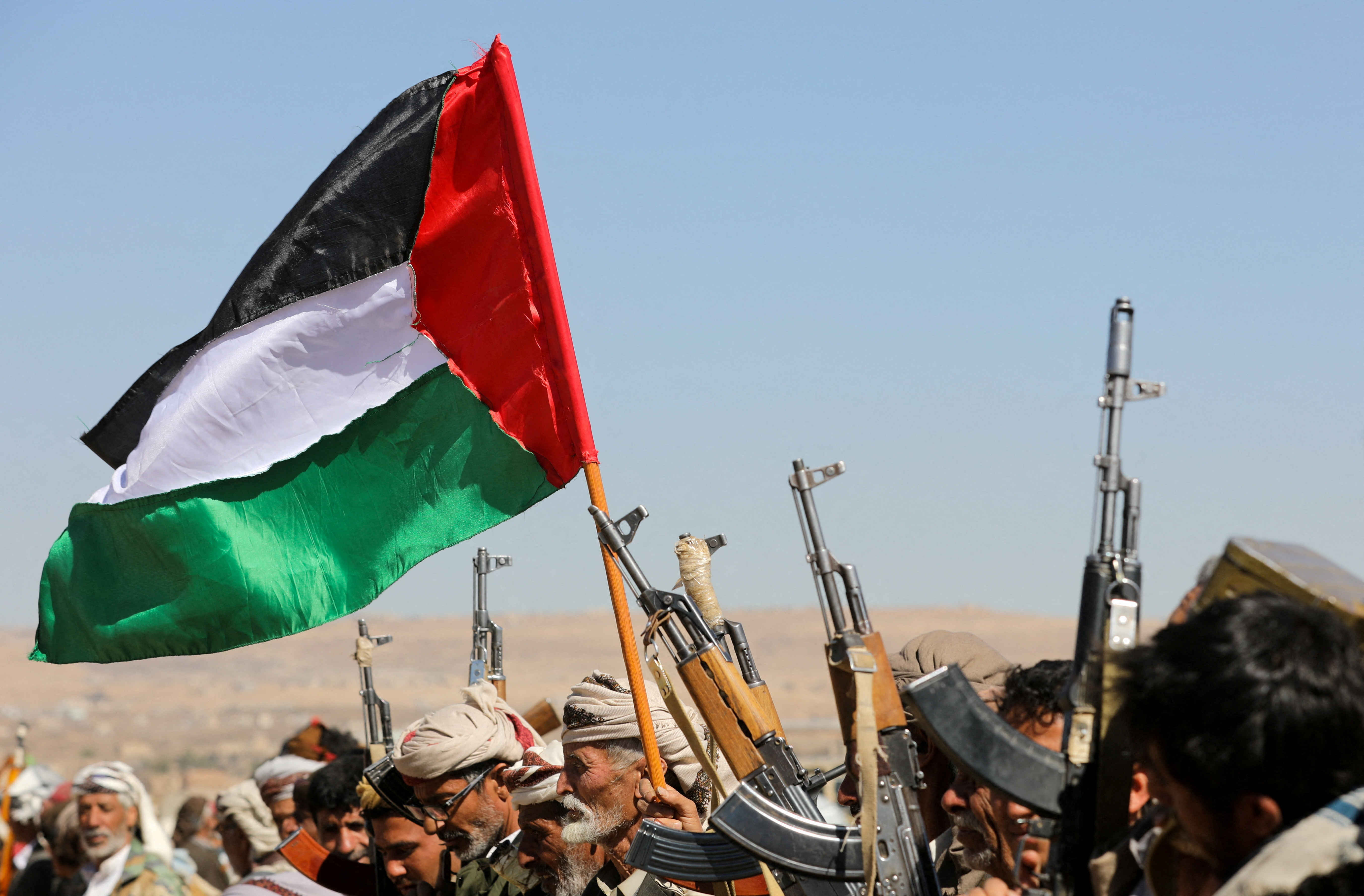 FILE PHOTO: Tribal supporters of Yemen's Houthis wave a Palestinian flag and hold up their firearms during a protest on recent U.S.-led strikes on Houthi targets, near Sanaa