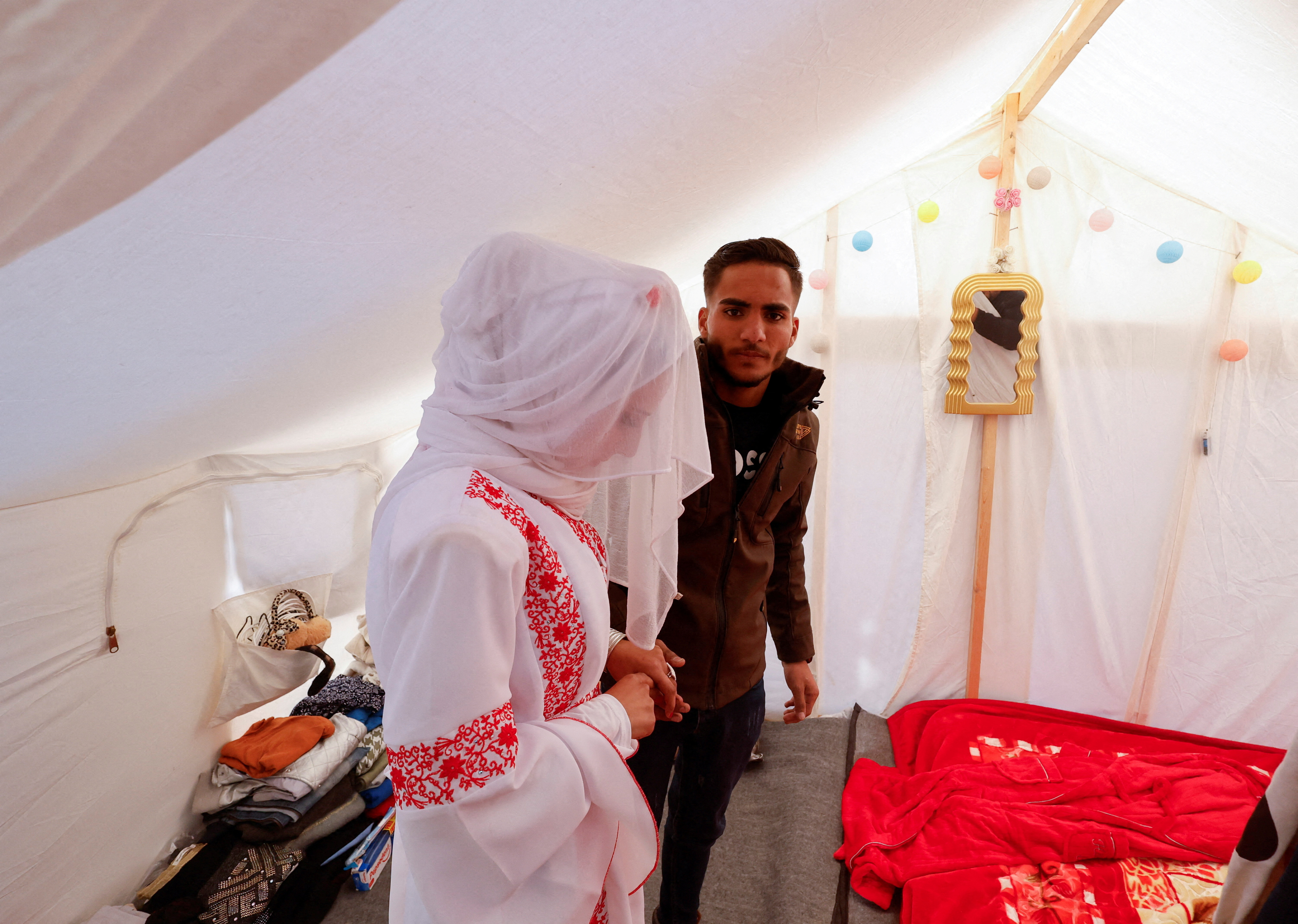A Palestinian couple stands in a tent camp on their wedding day in Rafah