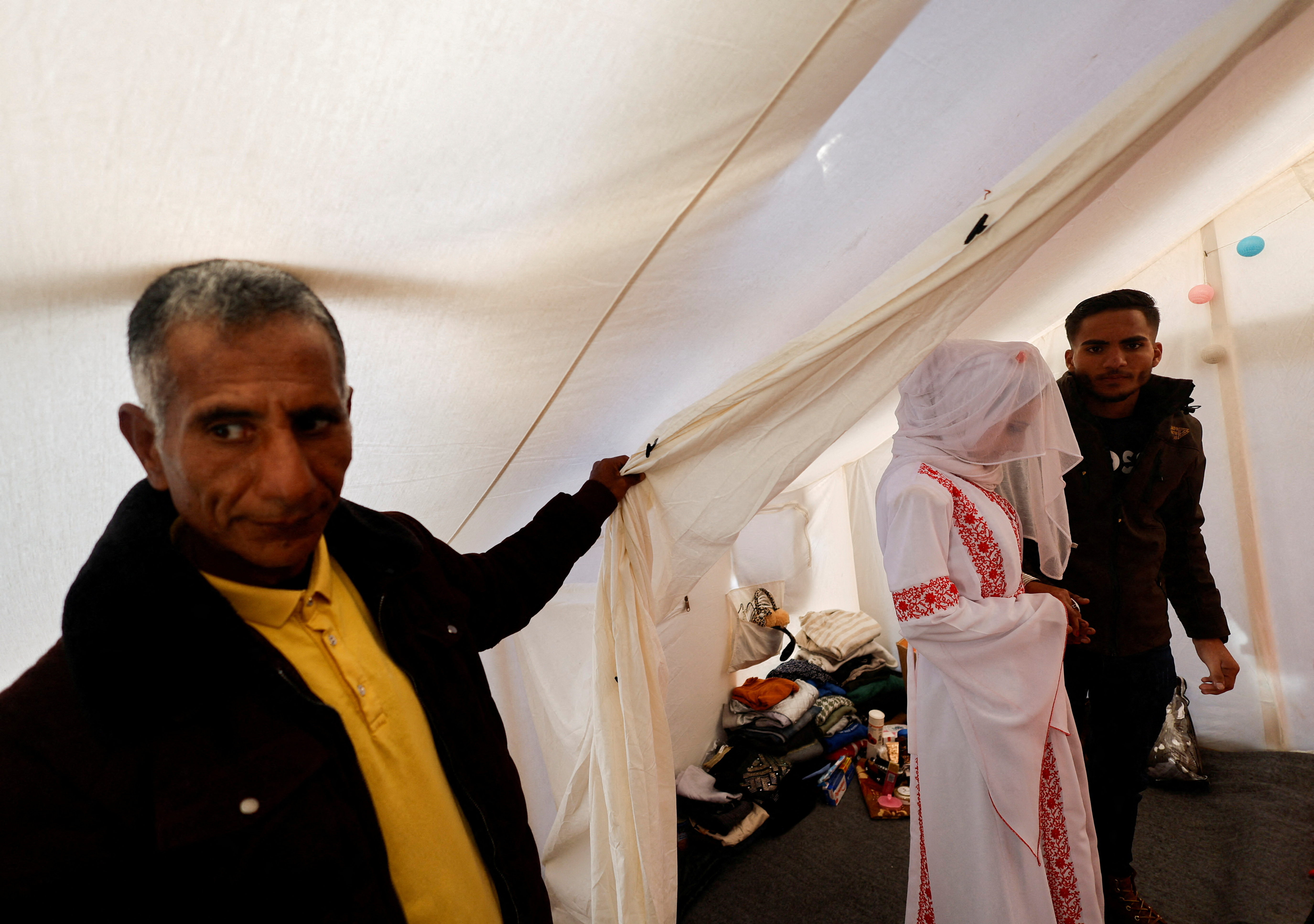 A Palestinian couple stands in a tent camp on their wedding day in Rafah