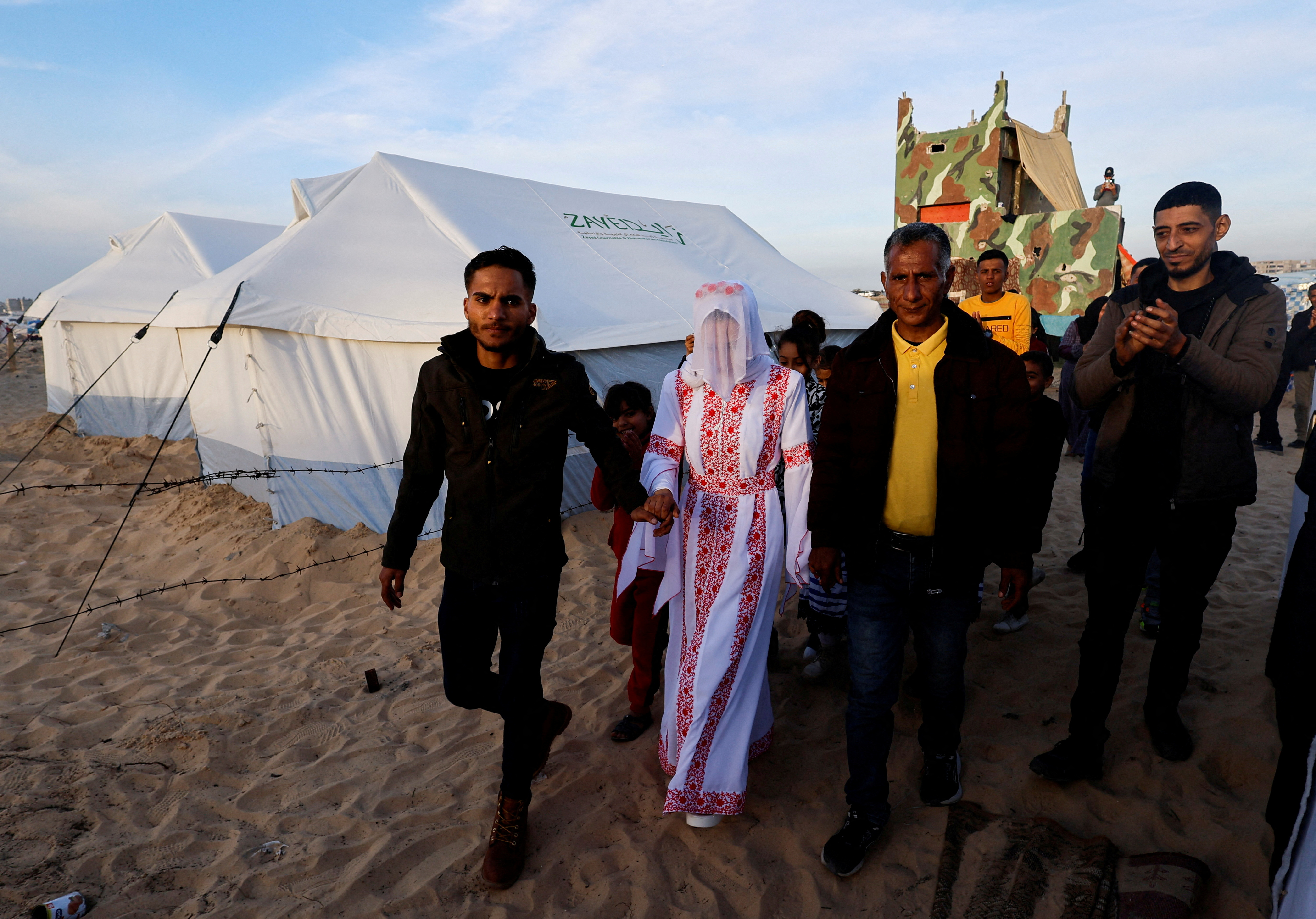 A Palestinian couple walks on their wedding day in the tent camp in Rafah