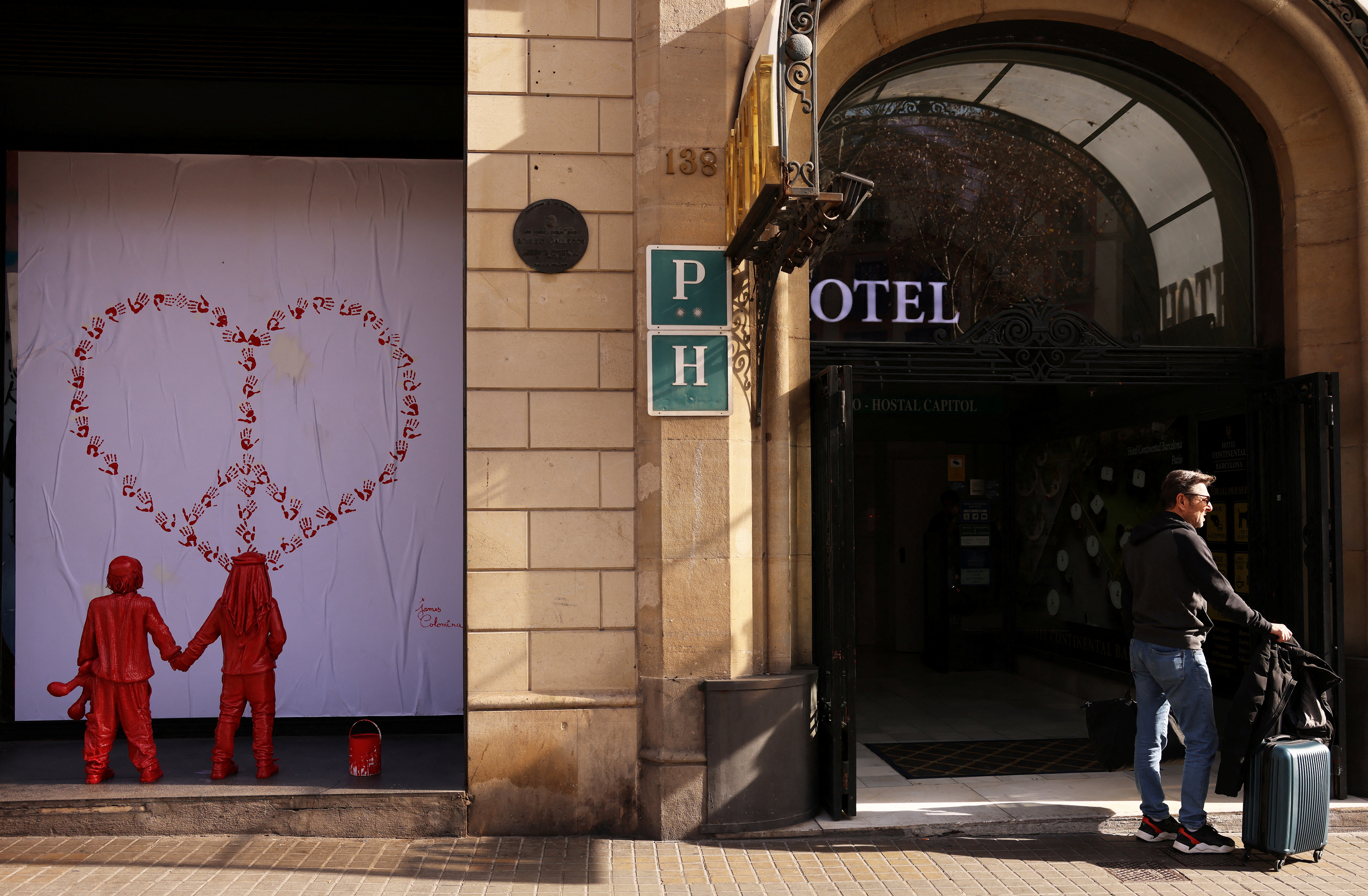 A tourist waits for taxi next to life-size statues of an installation entitled "Children of Peace",in Barcelona