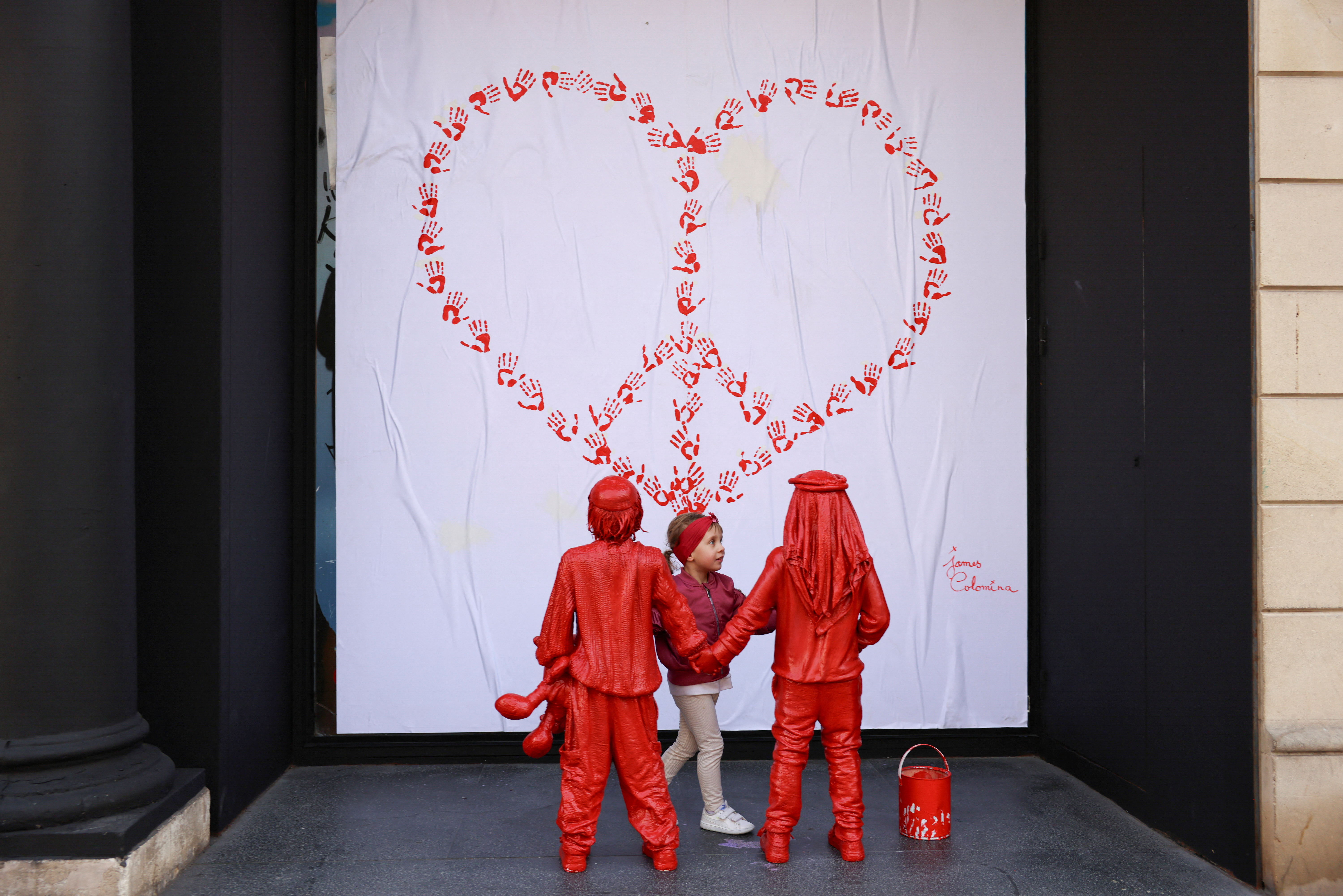 Olivia, 3, from Poland, embraces life-size statues of an installation representing the hope of the Israeli-Palestinian conflict, in Barcelona