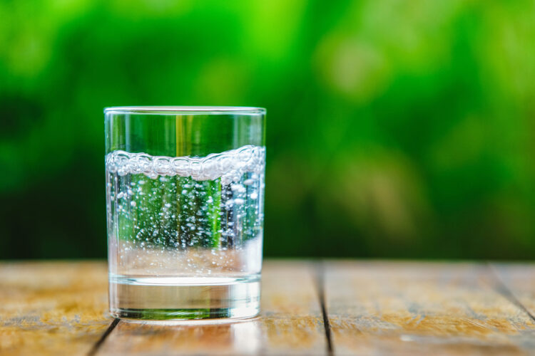 A,Glass,Of,Water,On,Green,Background.,The,Wooden,Table.