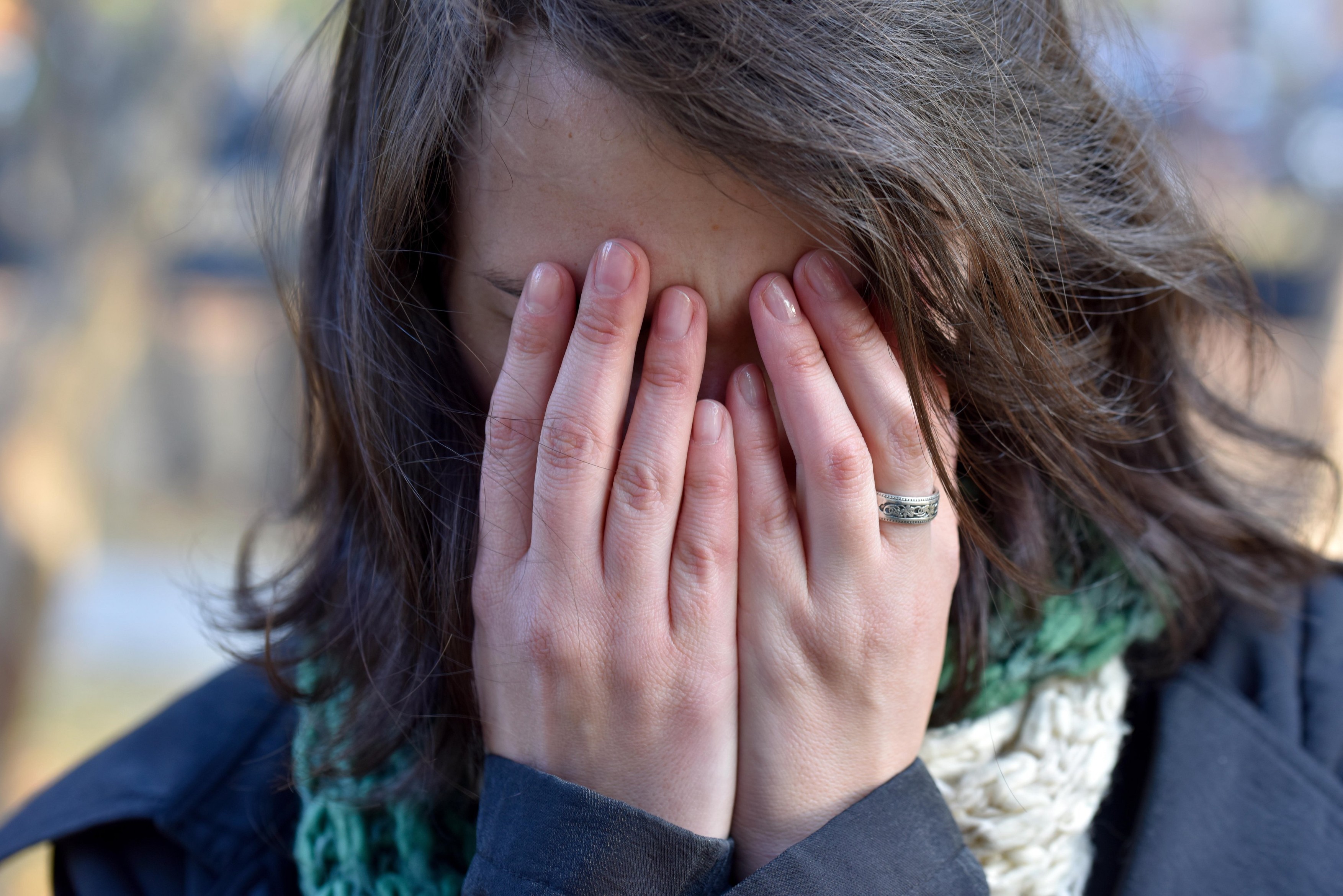Girl with dark hair covers face  her hands