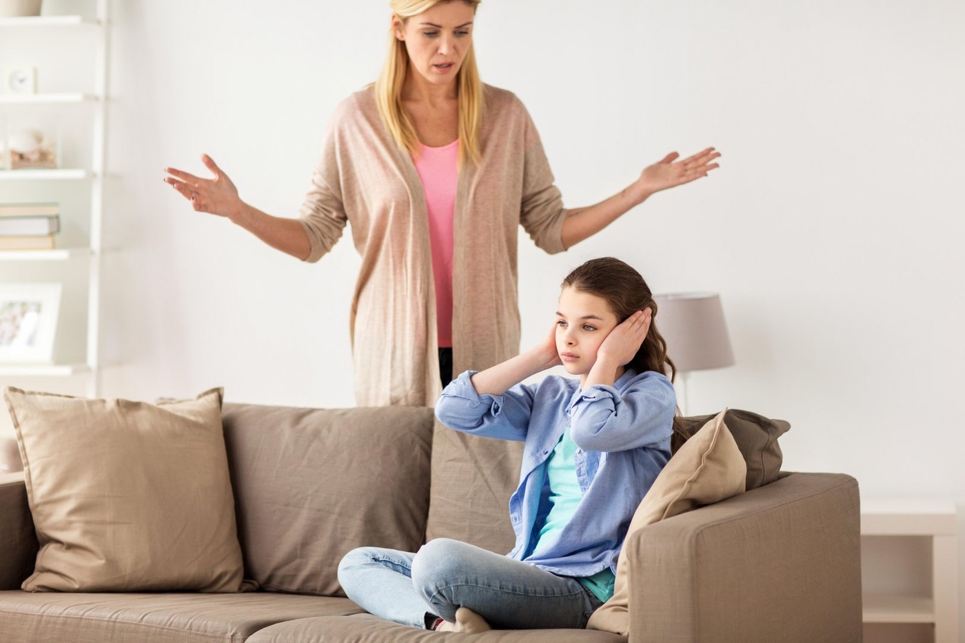girl closing ears to not hear angry mother at home