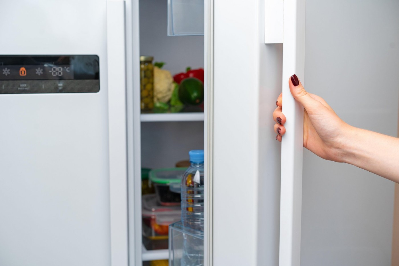 Female hand opens door of a fridge