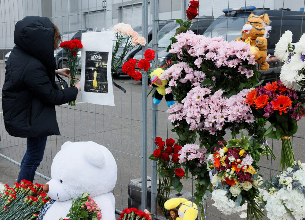 People lay flowers at a makeshift memorial to the victims of a shooting attack at a concert hall outside Moscow