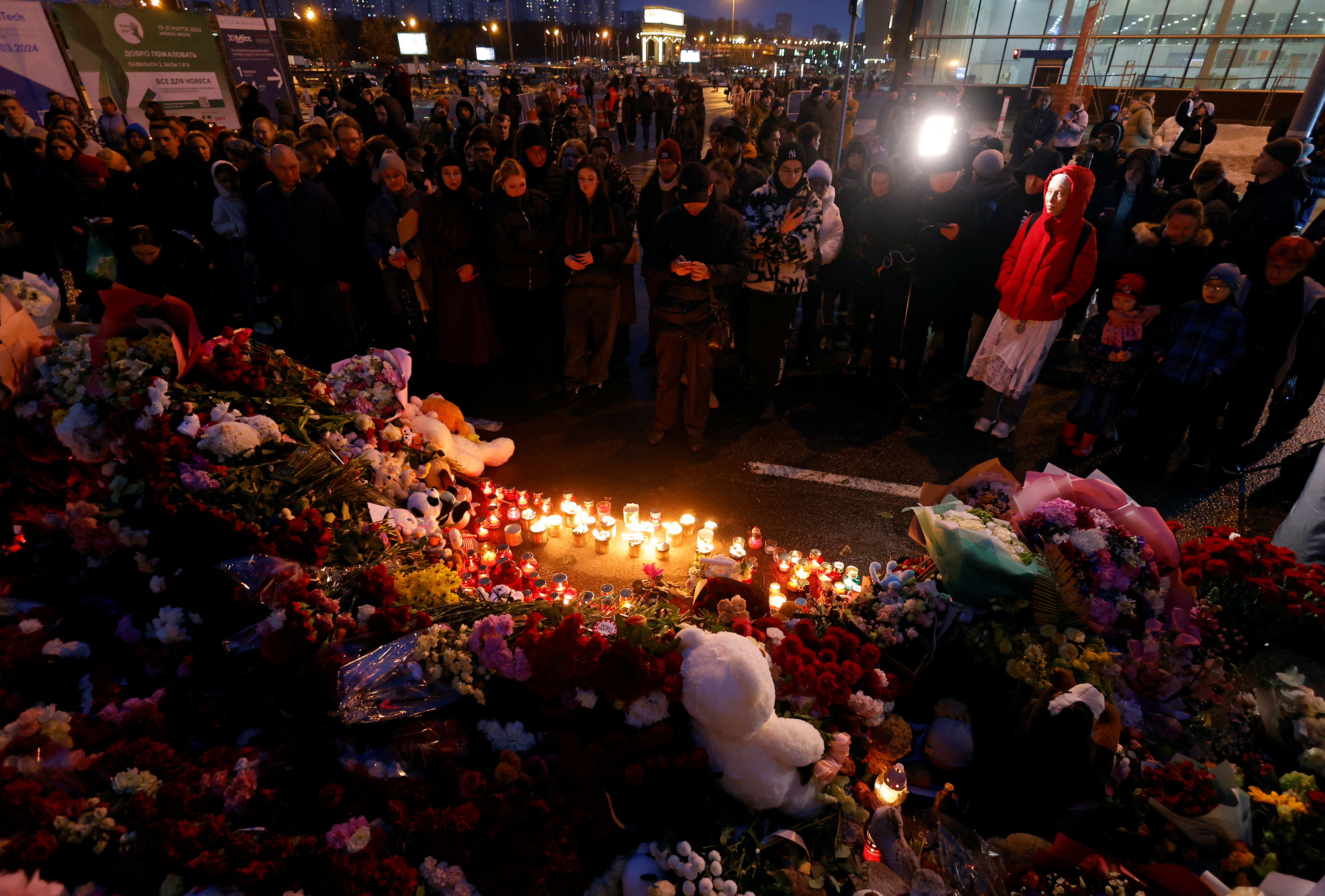 People lay flowers at a makeshift memorial to the victims of a shooting attack at a concert hall outside Moscow