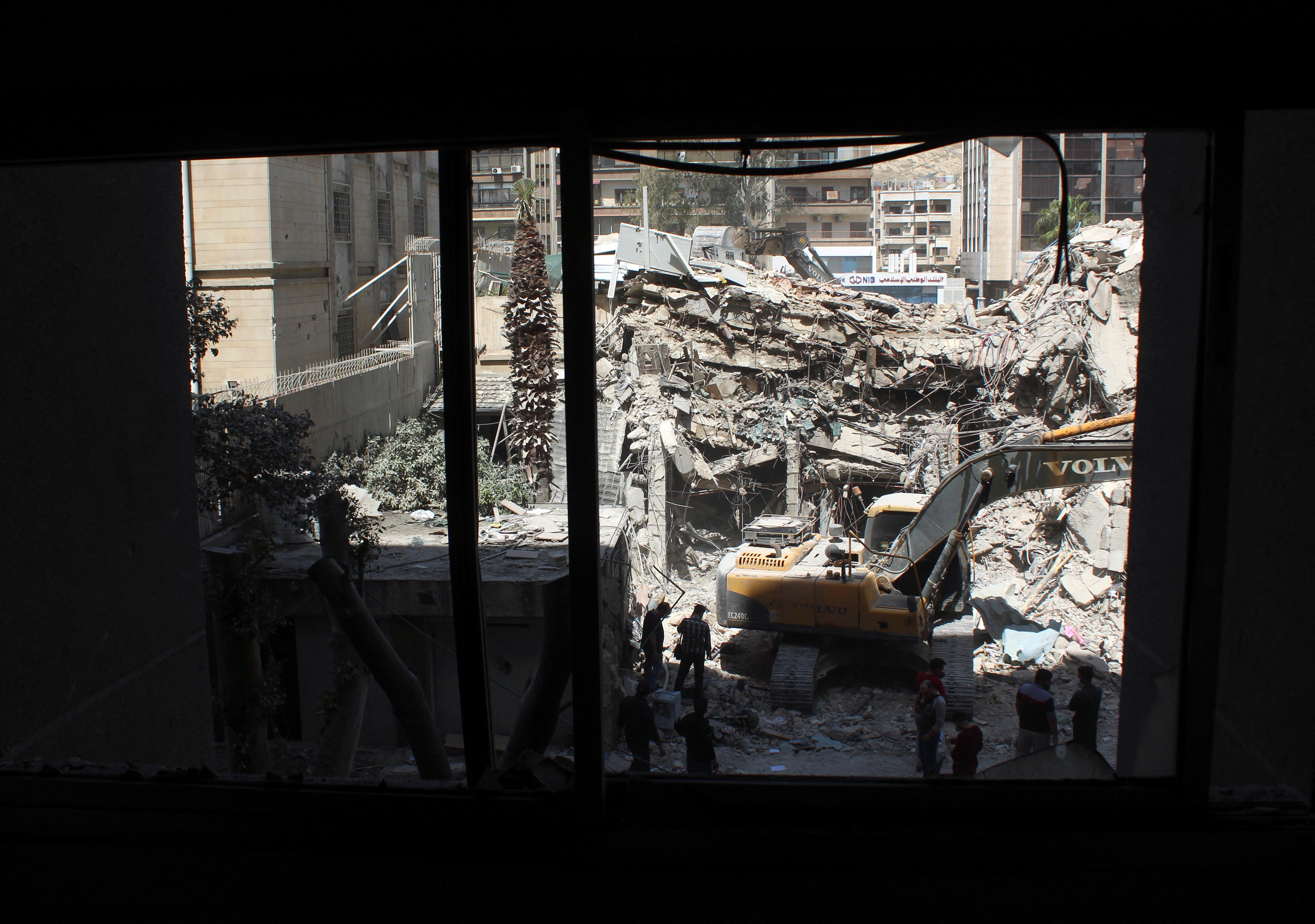 An excavator clears rubble after a suspected Israeli strike on Iran's consulate, in Damascus