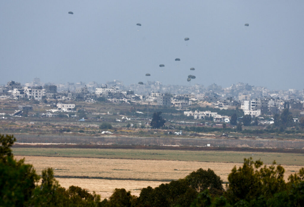 Humanitarian aid falls through the sky towards the Gaza Strip, as seen from Israel