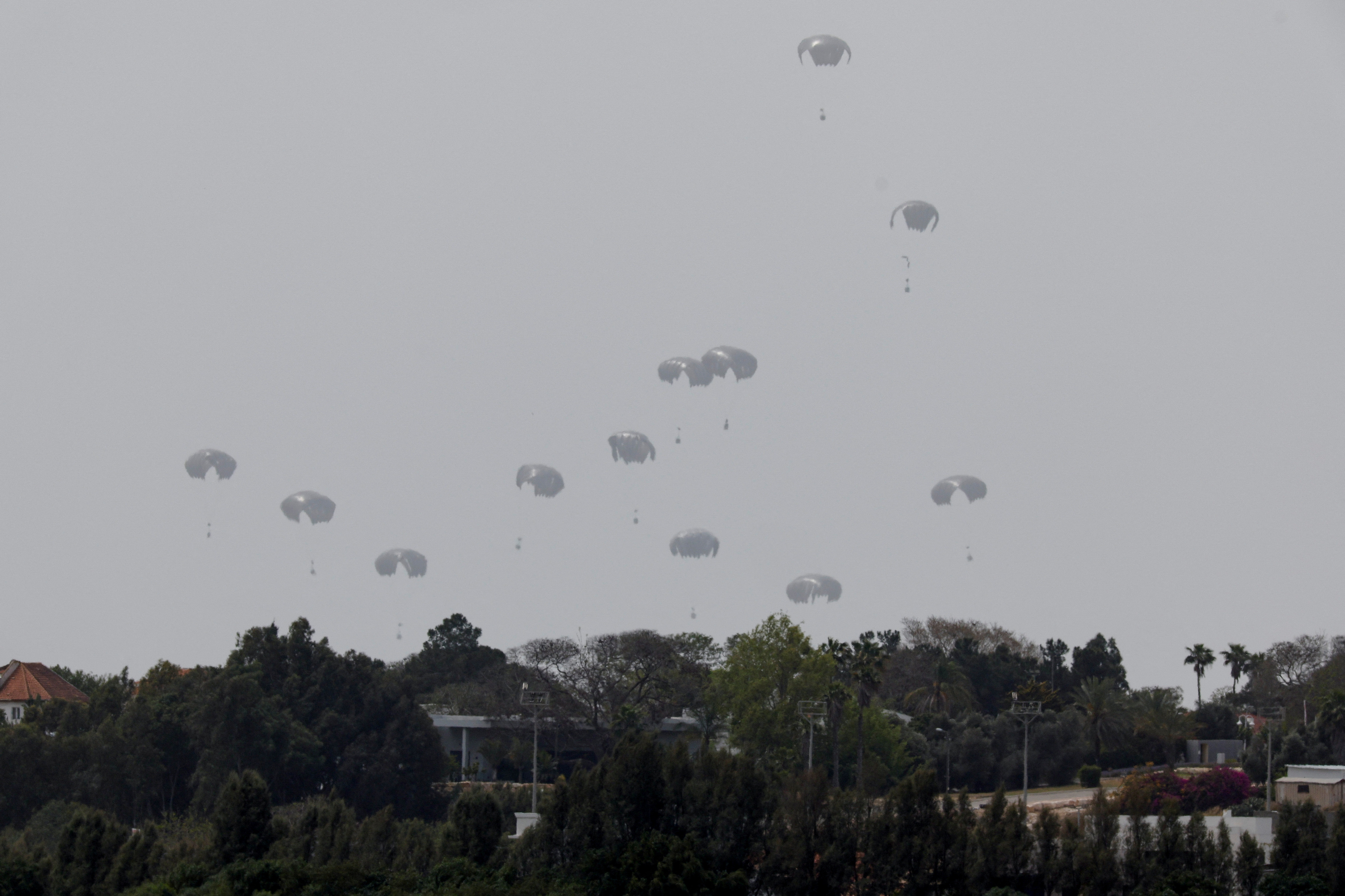 Humanitarian aid falls through the sky towards the Gaza Strip