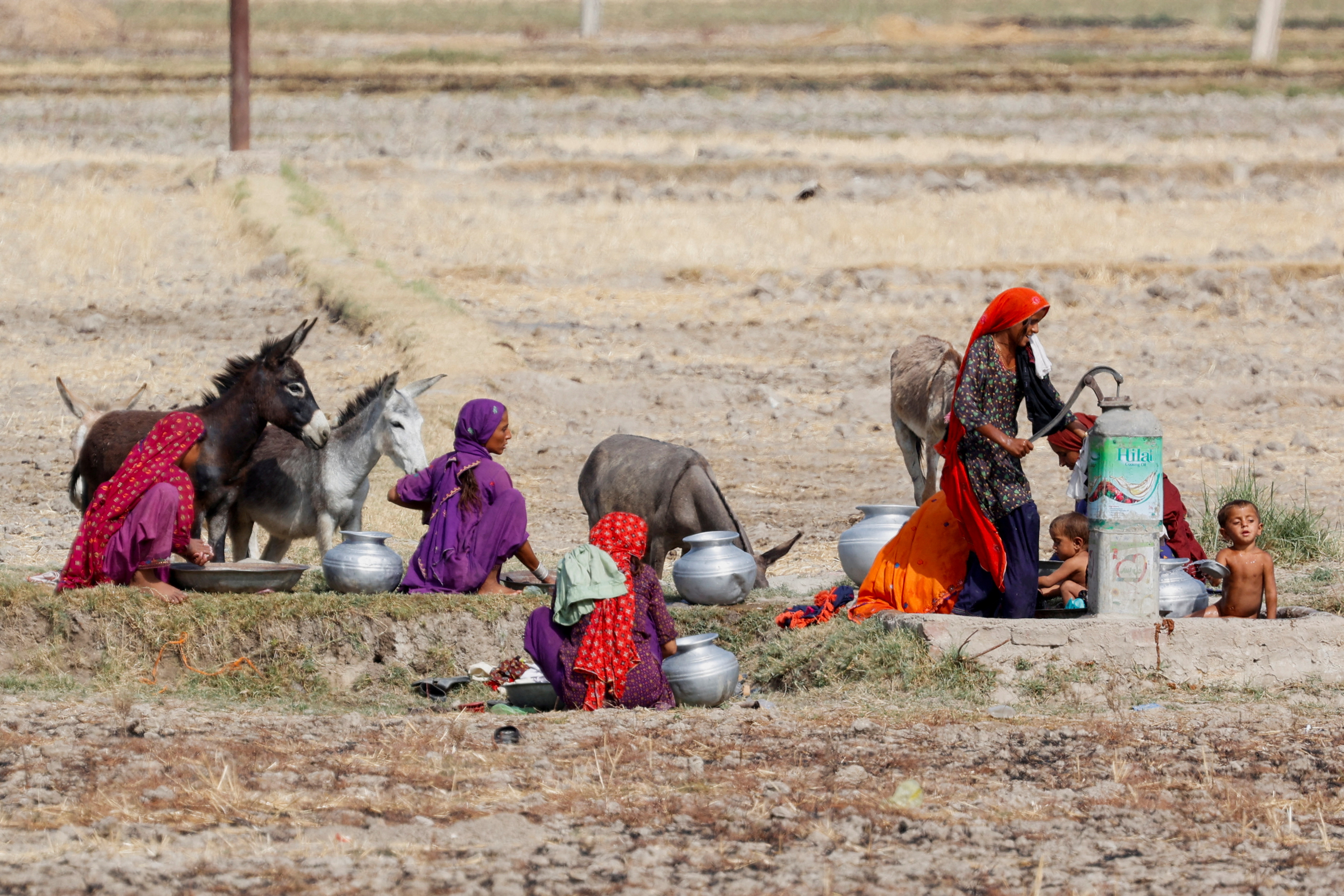 Women gather for washing and to fetch water at a handpump during a hot summer day on the outskirts of Larkana