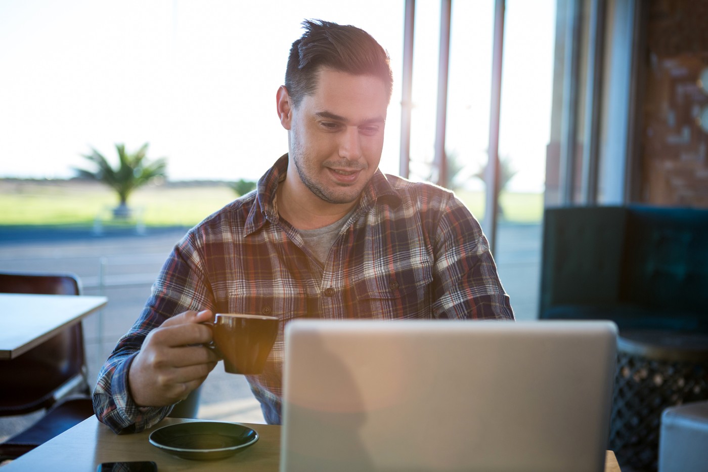 Smiling man using laptop while having coffee