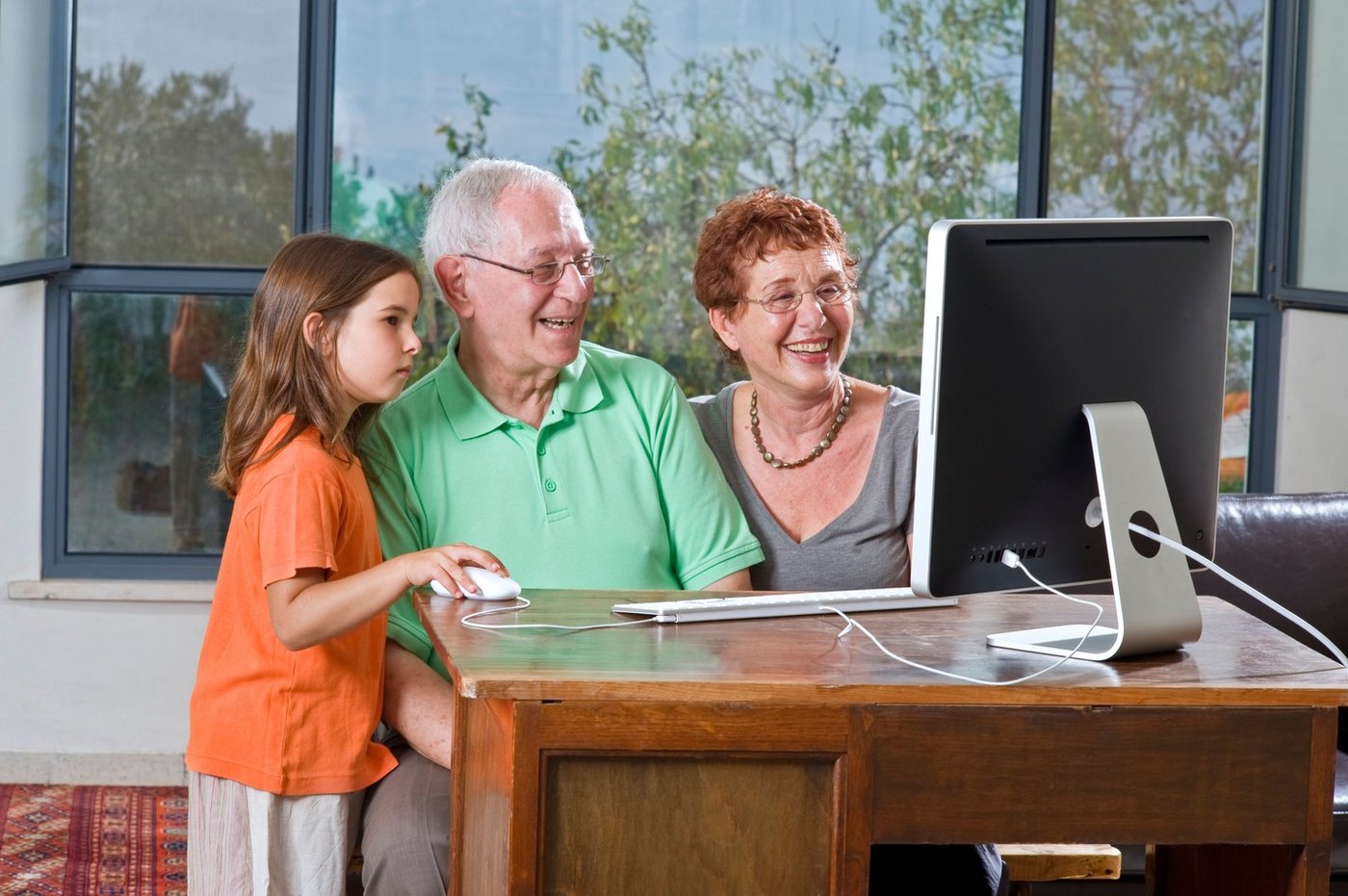 grandparents and granddaughter with computer at home