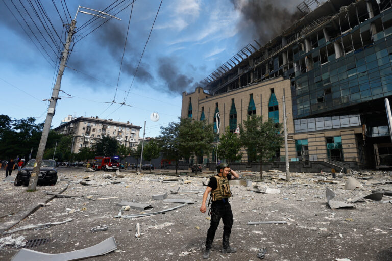 A man stands near a burning building that was damaged during Russian missile strikes, in Kyiv