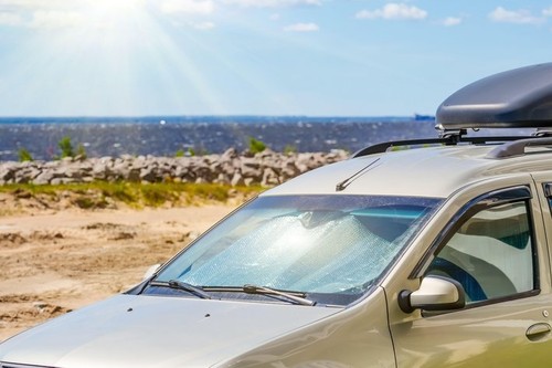 Protective reflective surface under the windshield of the passenger scar parked on a hot day, heated by the sun's rays inside on sea ocean coast beach