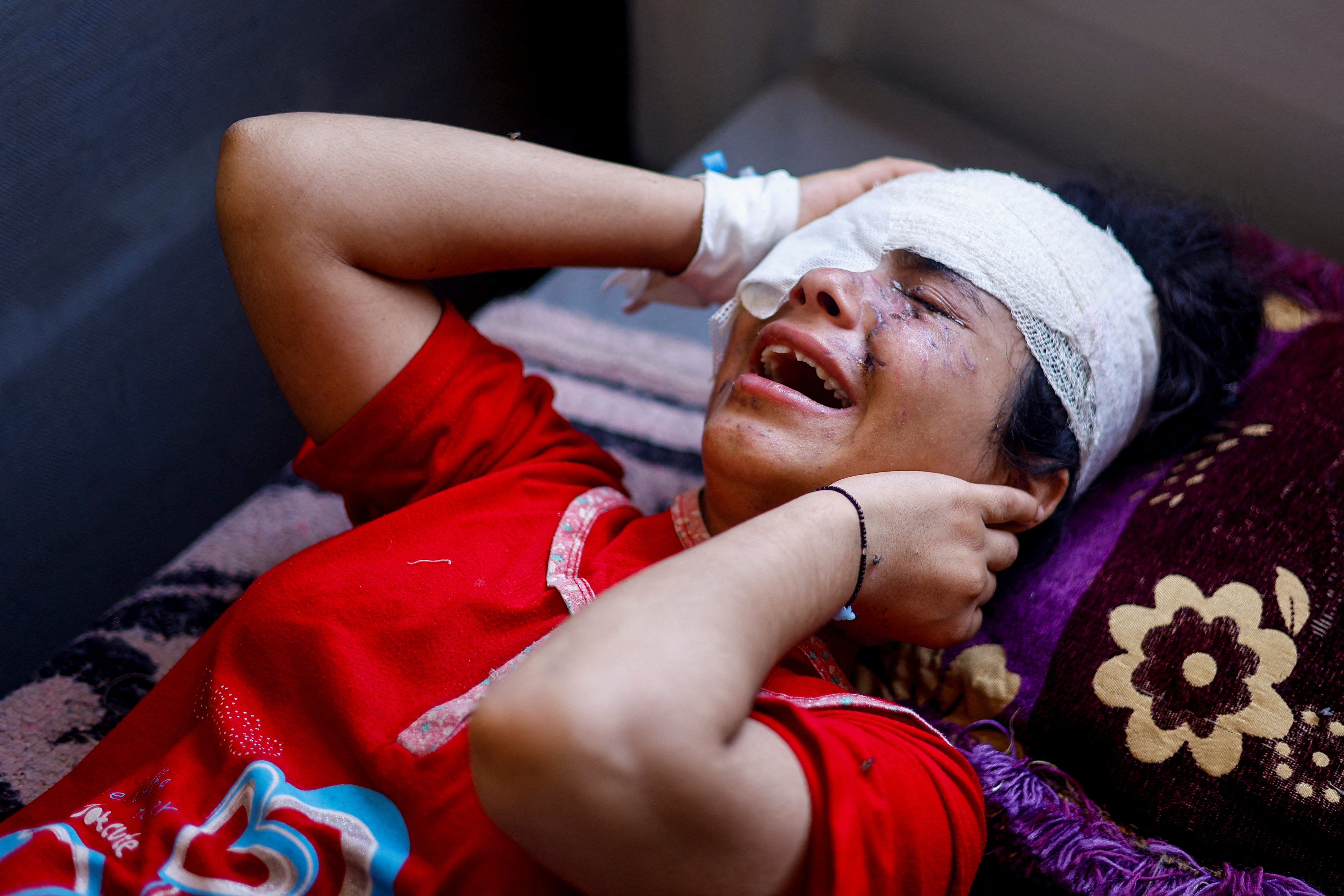 Palestinian girl Maisa Al-Ghandour, who was wounded in an Israeli strike along with her two siblings and mother, cries on a bed at Nasser hospital, in Khan Younis in the southern Gaza Strip