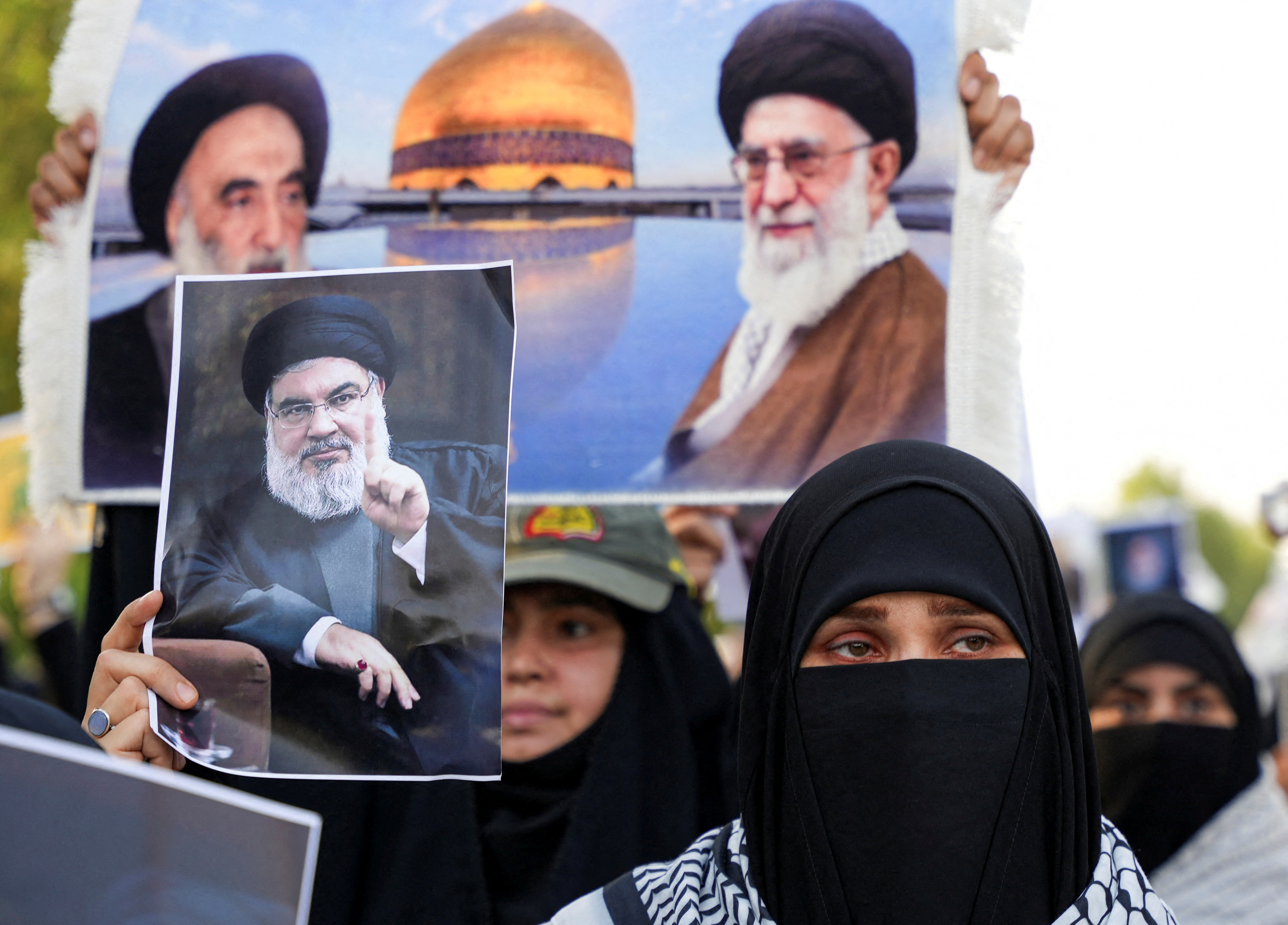 A woman holds a picture of Lebanon's Hezbollah Chief Hassan Nasrallah who was killed by an Israeli airstrike in Beirut, during a symbolic funeral in Basra