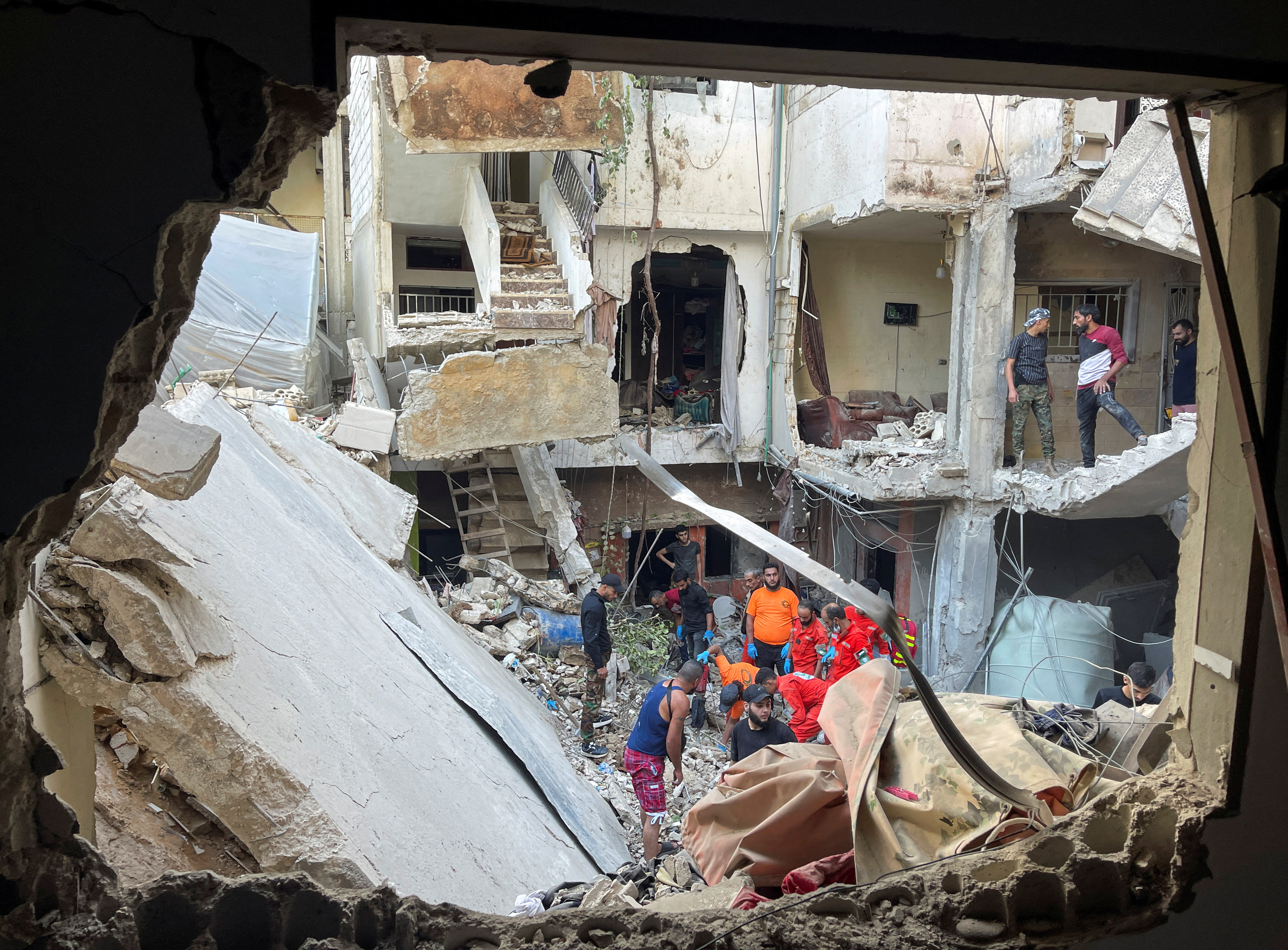 Rescuers and people inspect the site of a strike in Ain al-Hilweh refugee camp, near the southern city of Sidon