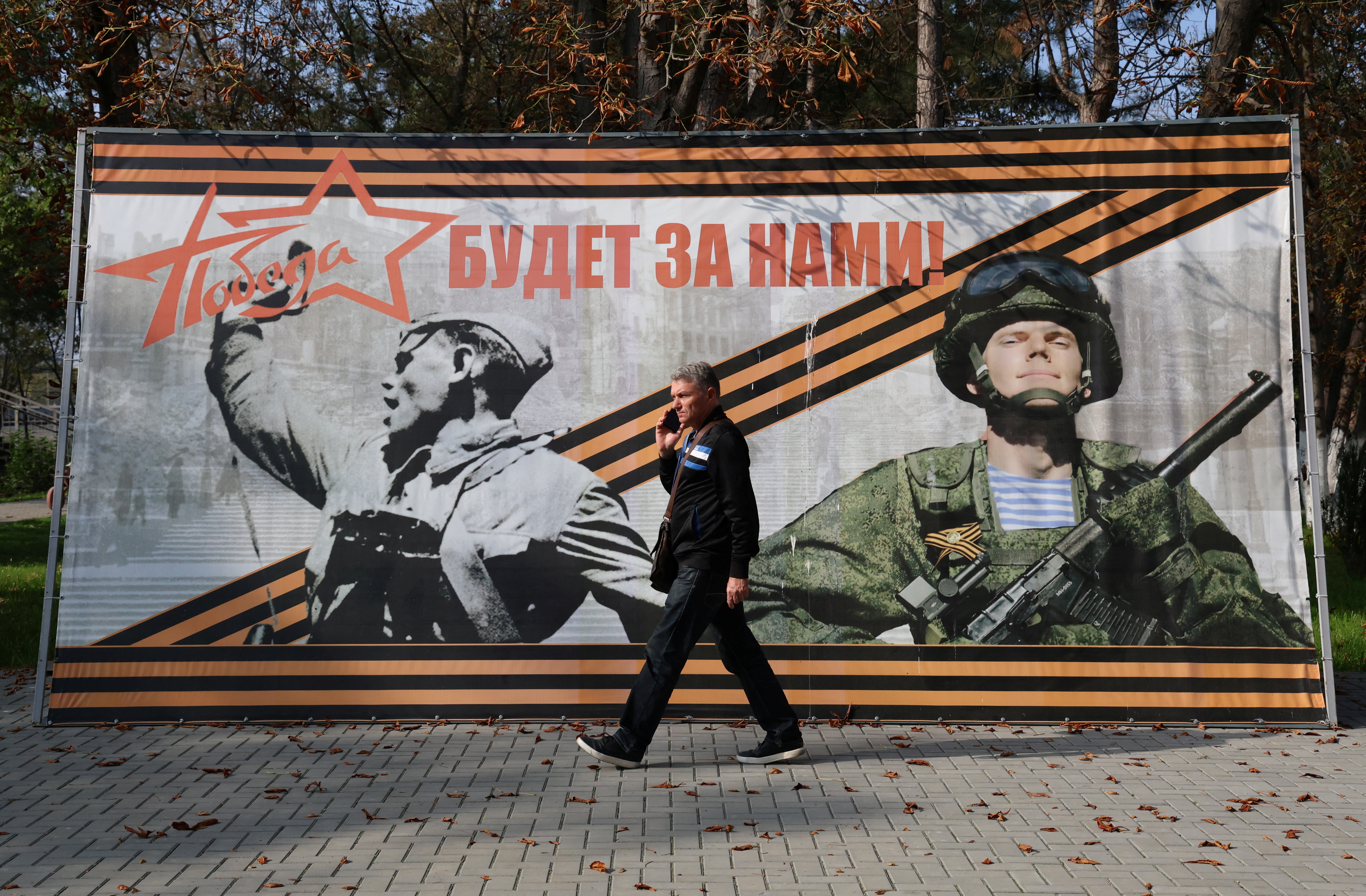 A man walks past a banner reading "Victory will be ours!" in the settlement of Sovetsky