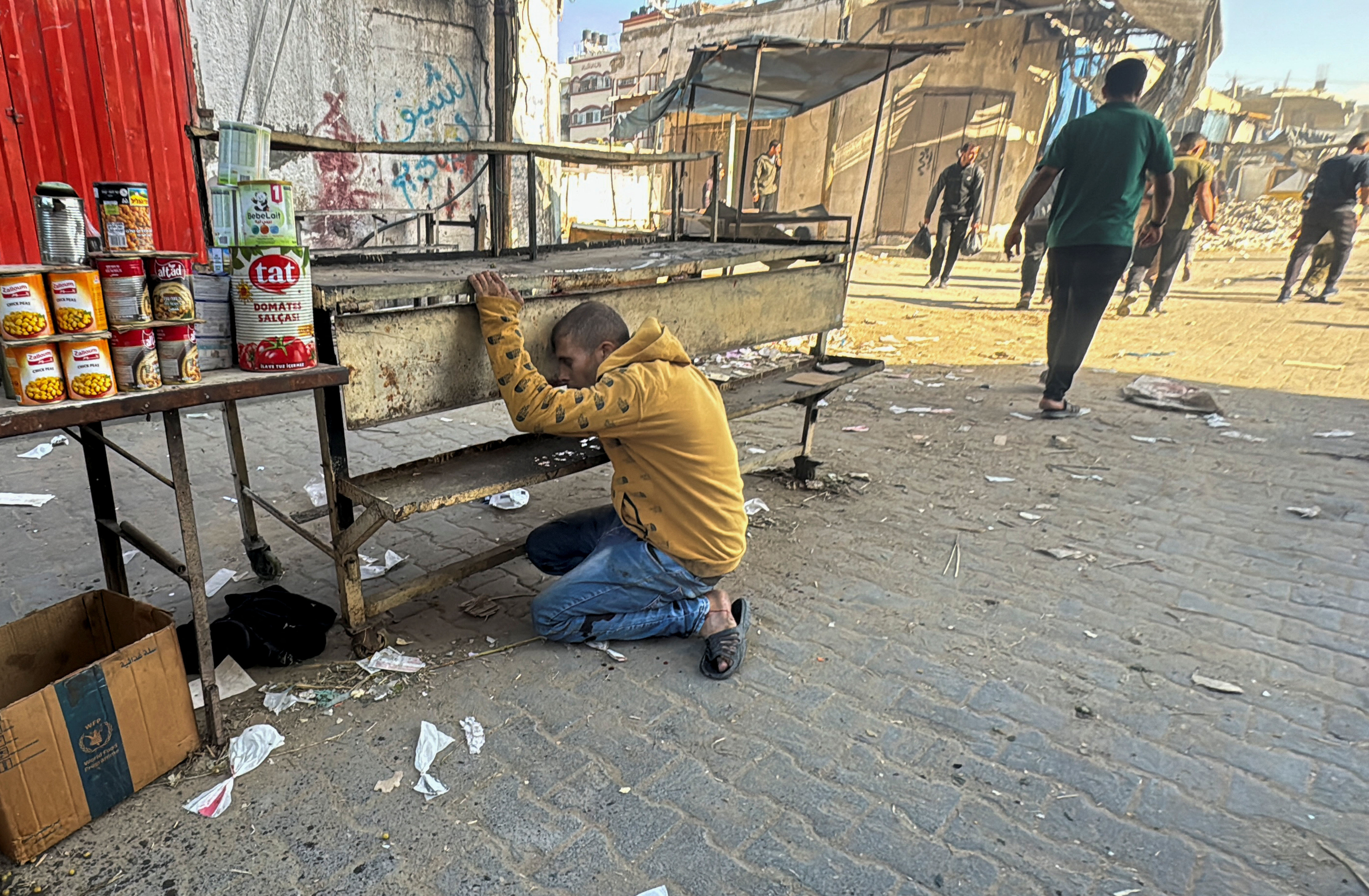 An injured Palestinian kneels on the ground following an Israeli strike, in Beit Lahiya