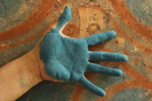 1733070069-Luis-May-Ku-49-places-the-back-of-his-hand-that-is-painted-in-Maya-Blue-against-a-fire-kiln-that-creates-the-pigment-in-Dzan-Yucatan-Mexico-on-9-September-2024_-1731947376-300x200.webp