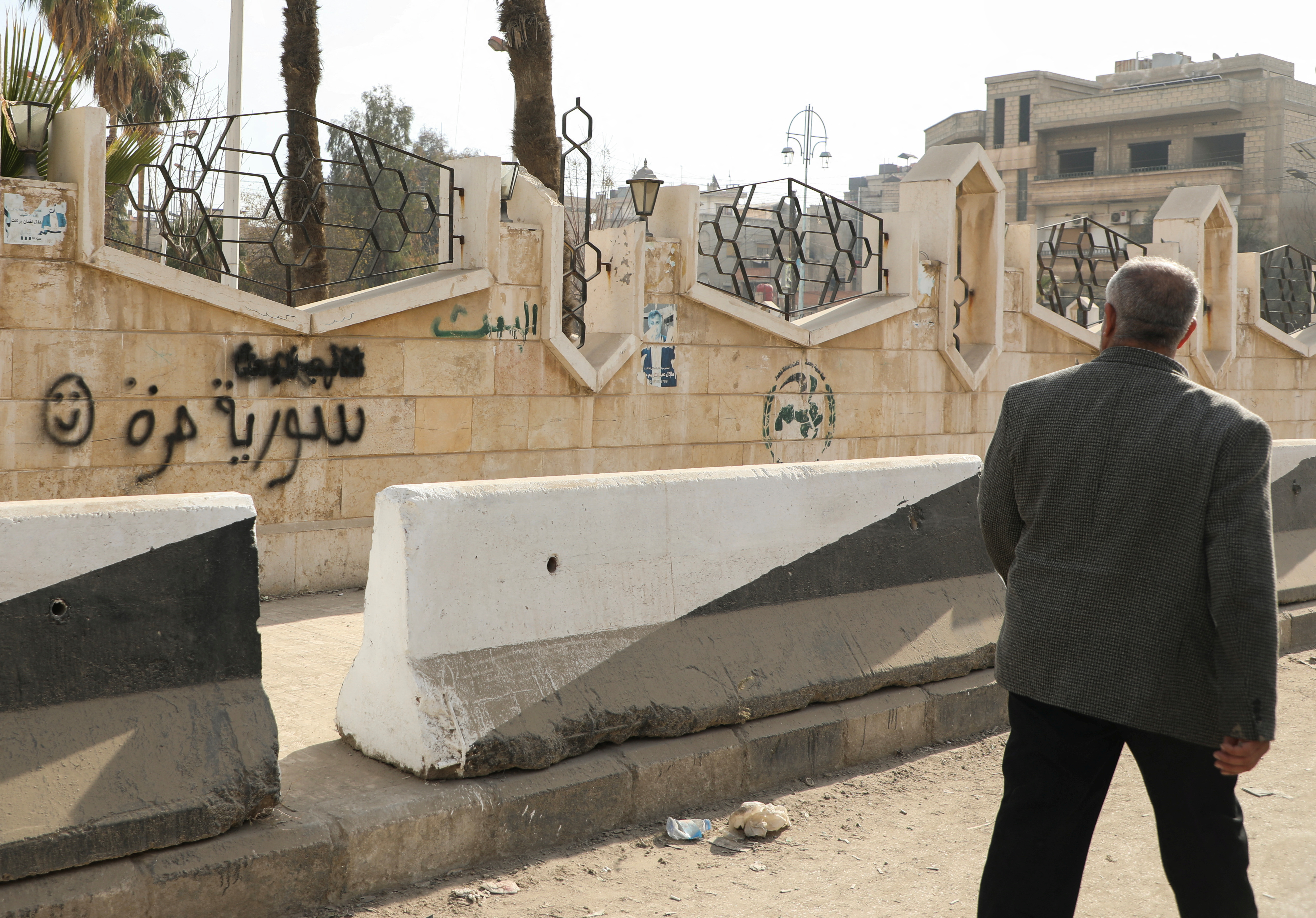 A man walks past a writing on the wall that reads 'Free Syria' in Hasakah