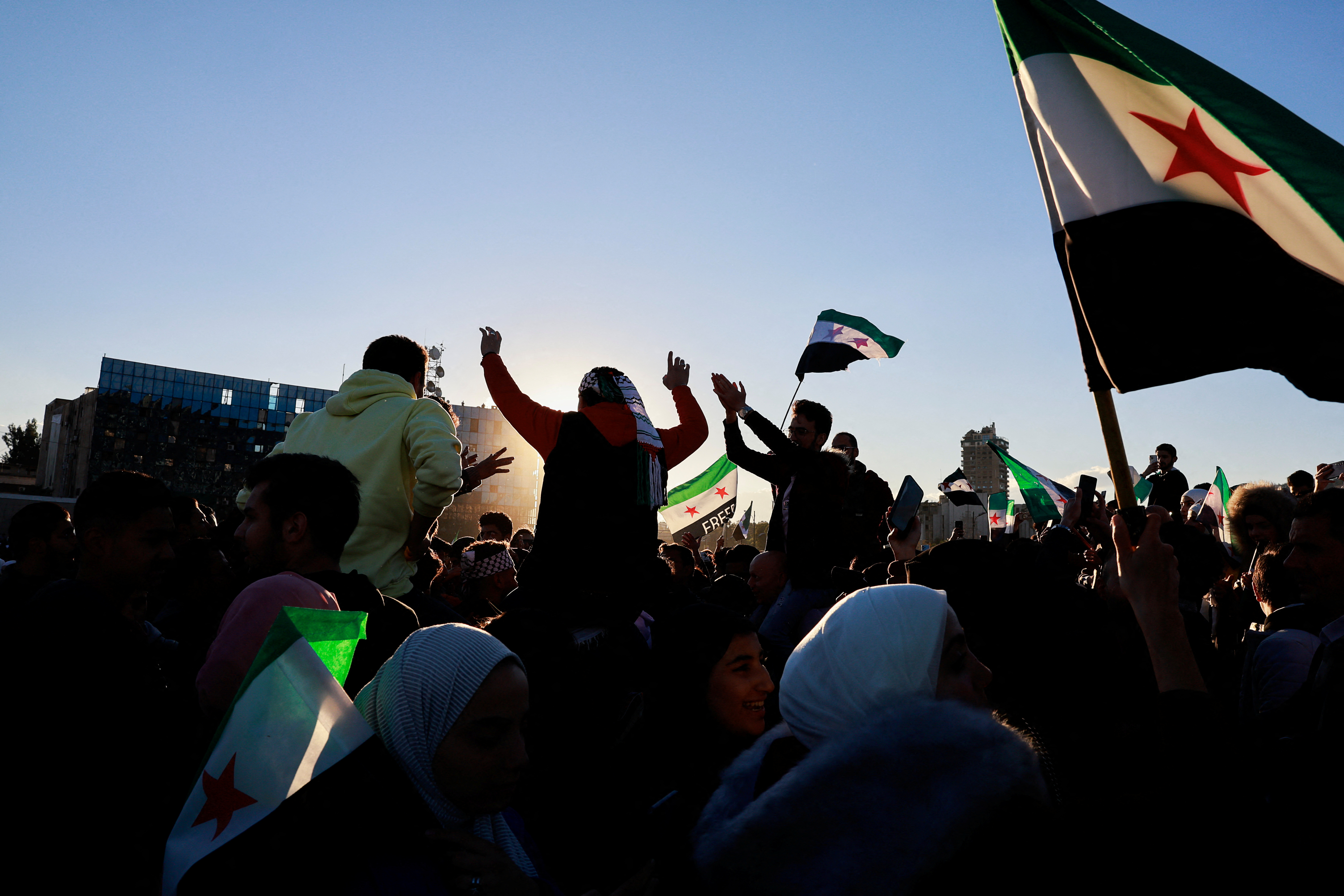 People celebrate after fighters of the ruling Syrian body ousted Syria's Bashar al-Assad, in Damascus
