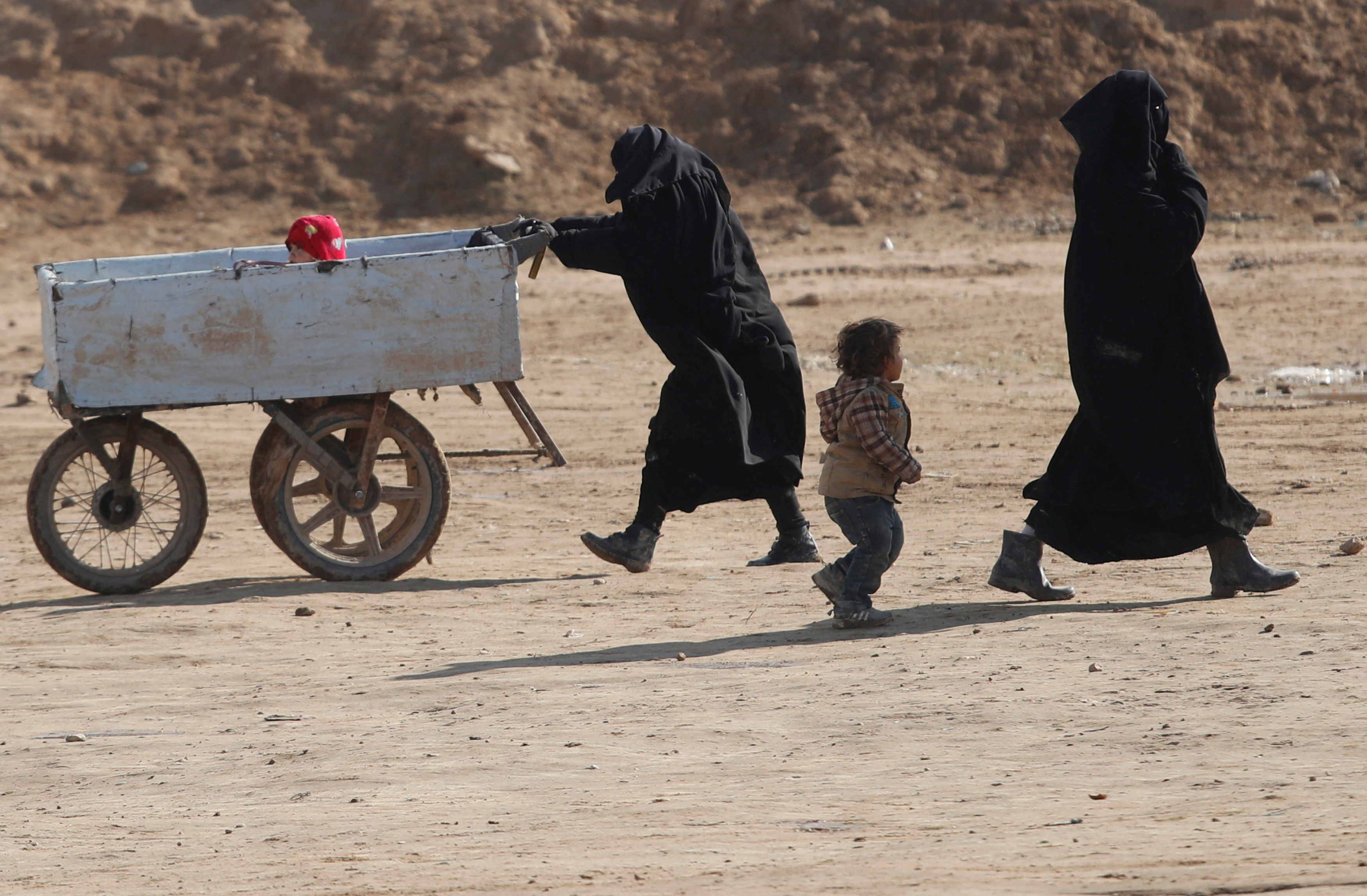 FILE PHOTO: Women and children walk through al-Hol camp in Syria
