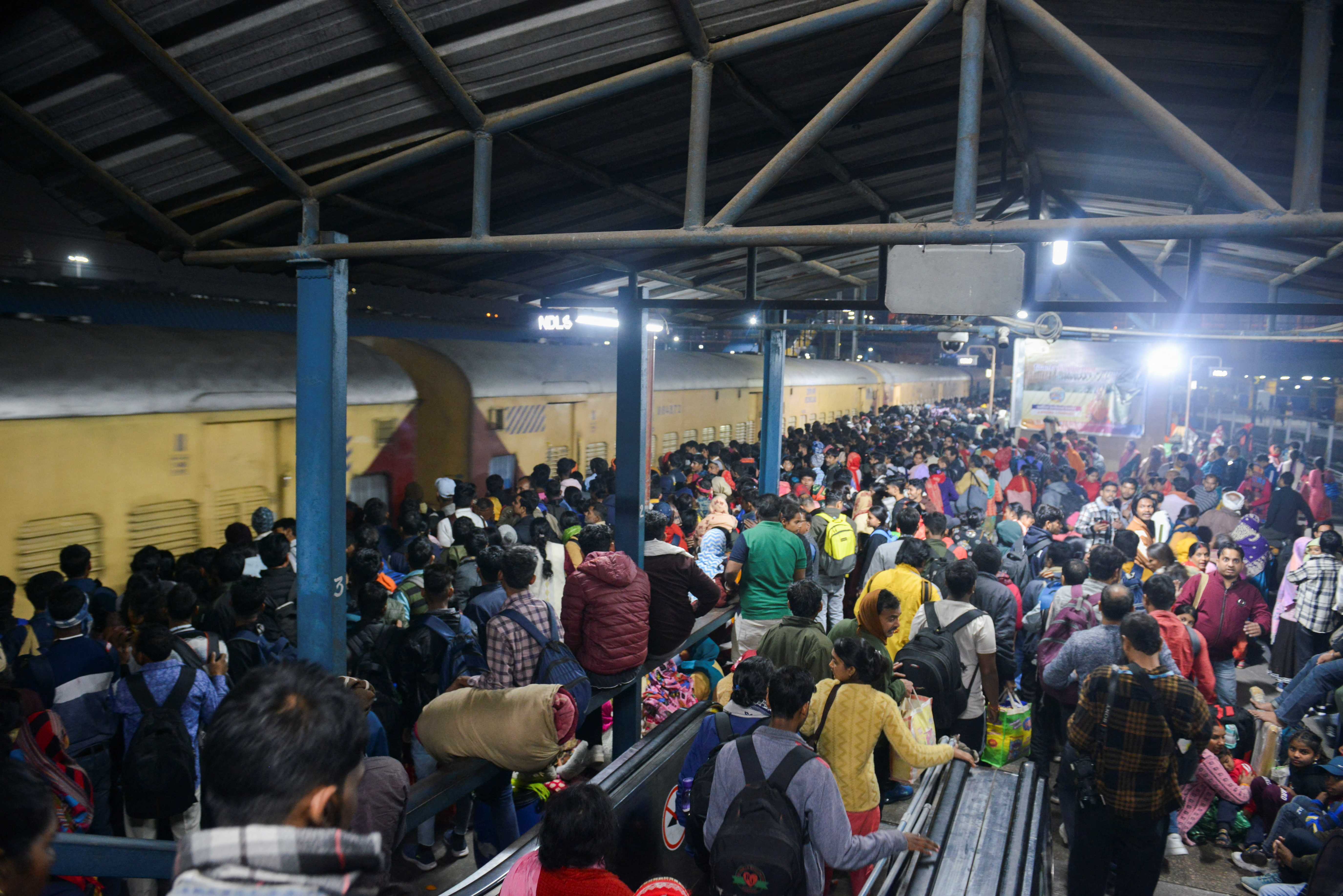 People, including Hindu pilgrims on their way to attend the "Maha Kumbh Mela", or the Great Pitcher Festival, gather at the New Delhi Railway Station to board a train