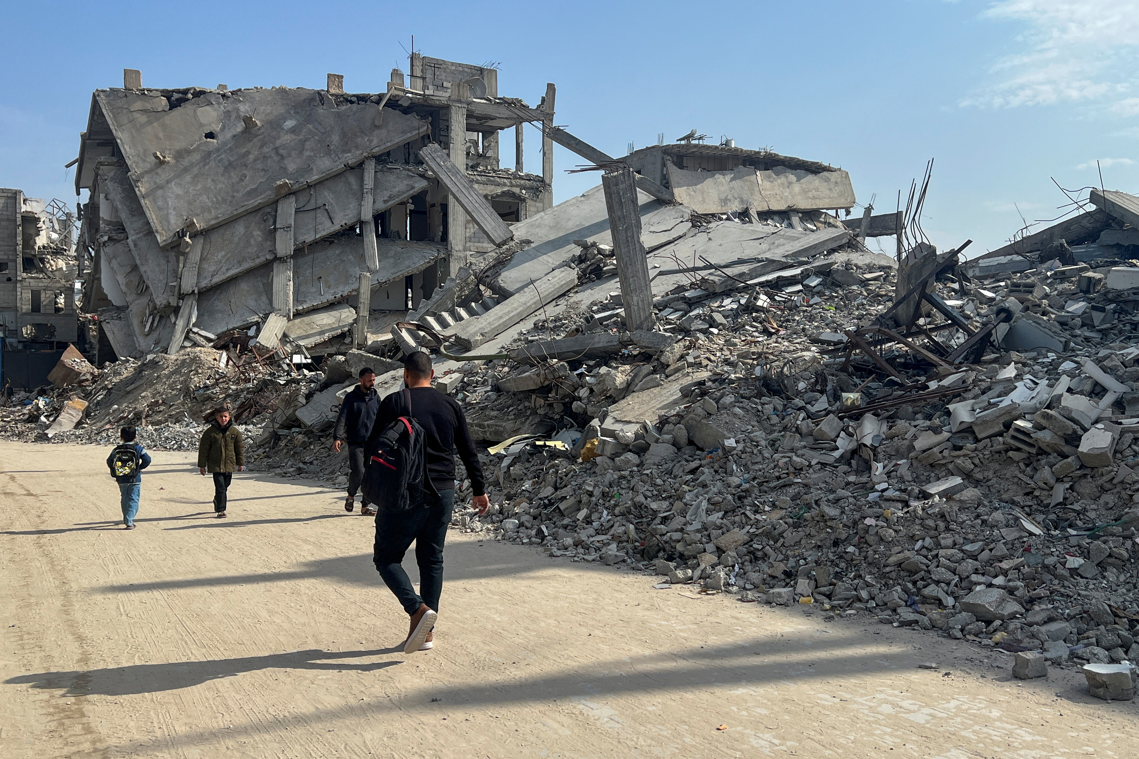 Palestinians walk past the rubble of destroyed houses, amid a ceasefire between Israel and Hamas, in Khan Younis in the southern Gaza Strip