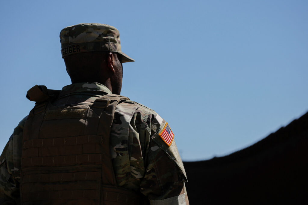 A member of the U.S. Army stands facing the border wall between Mexico and the United States, whcih has been reinforced by the U.S. Military, in San Dieg