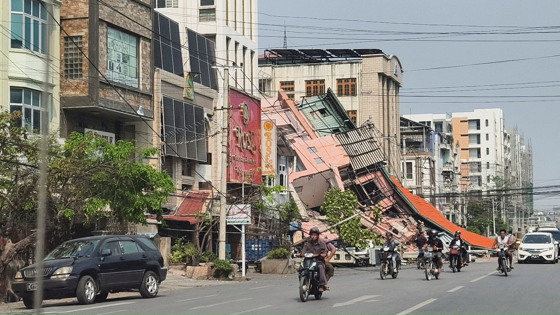 People ride motorcycles past a damaged building after a strong earthquake struck central Myanmar, in Mandalay