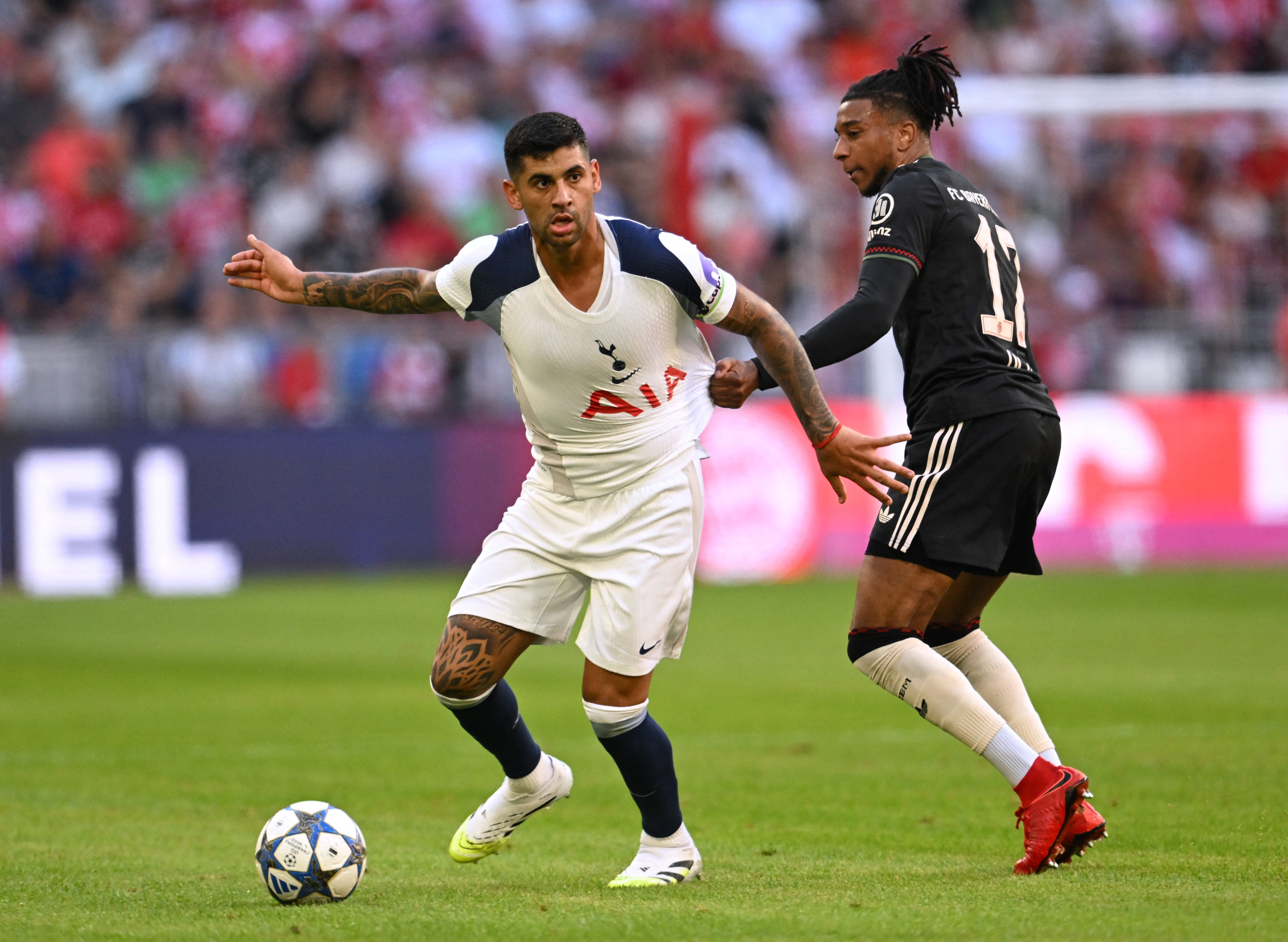 Soccer Football - Friendly Match - Bayern Munich v Tottenham Hotspur - Allianz Arena, Munich, Germany - August 7, 2025 Tottenham Hotspur's Cristian Romero in action with Bayern Munich's Michael Olise REUTERS/Angelika Warmuth