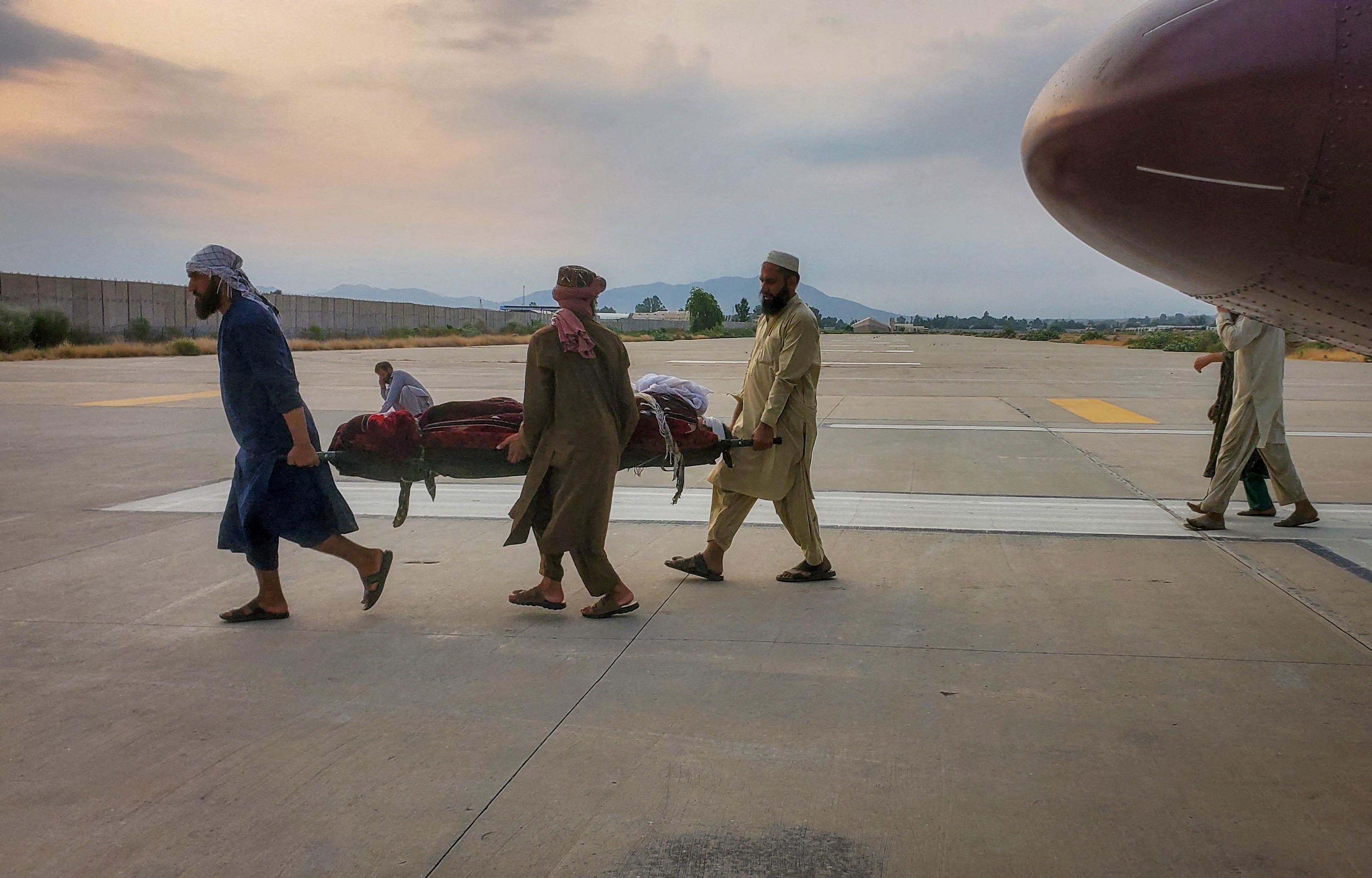 People carry an earthquake victim on a stretcher to an ambulance at an airport in Jalalabad, Afghanistan